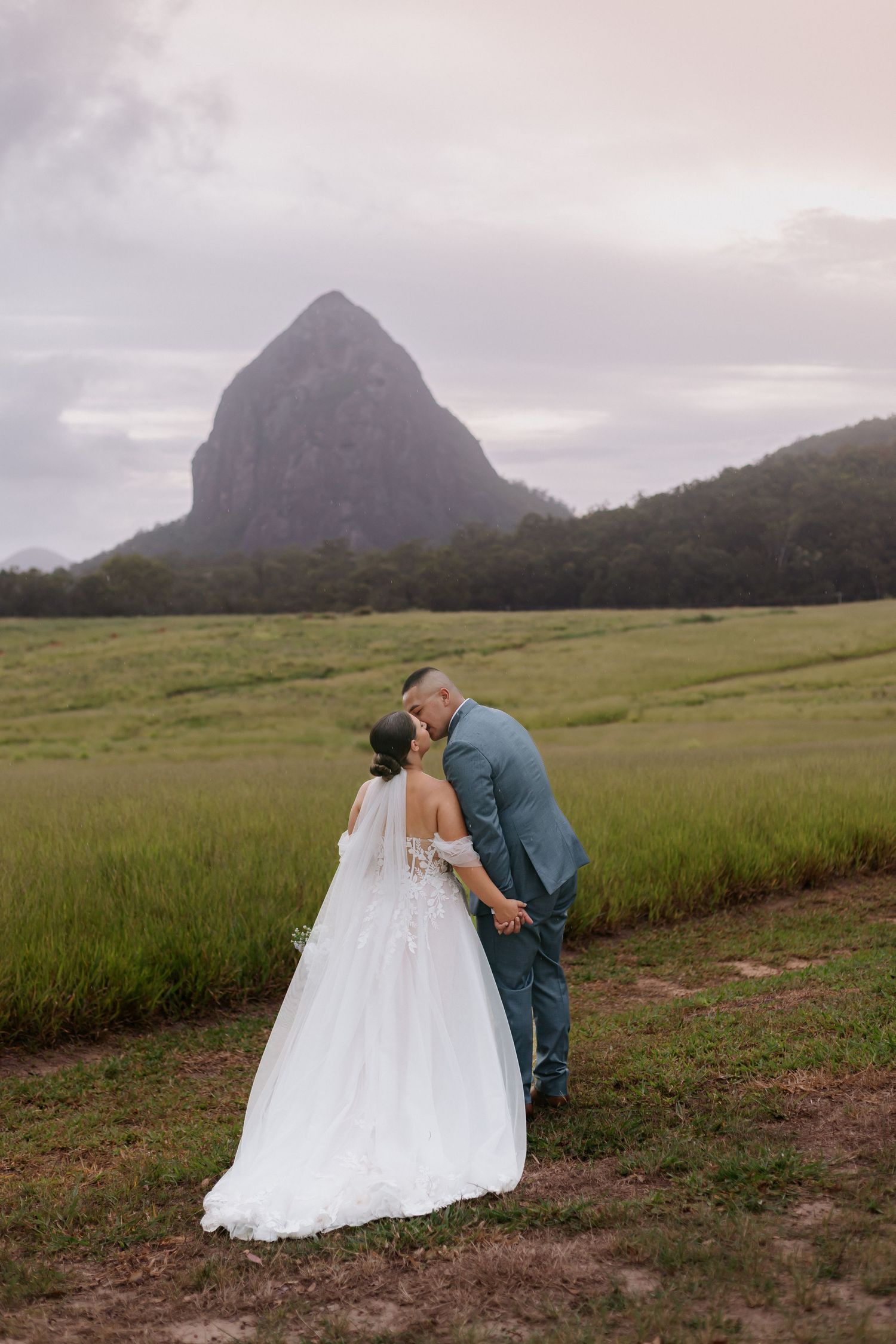 A couple shares a romantic moment in front of the iconic Glass House Mountains in Queensland, Australia.