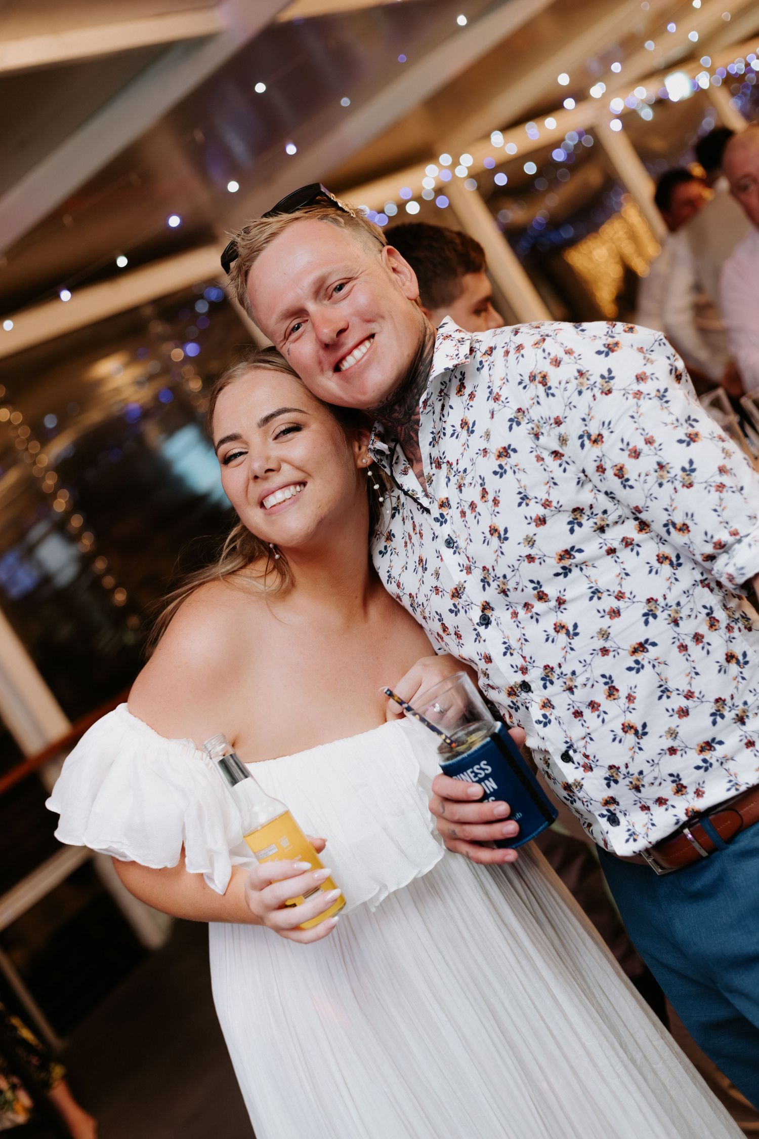 A couple dancing and embracing at a wedding reception under twinkling lights.