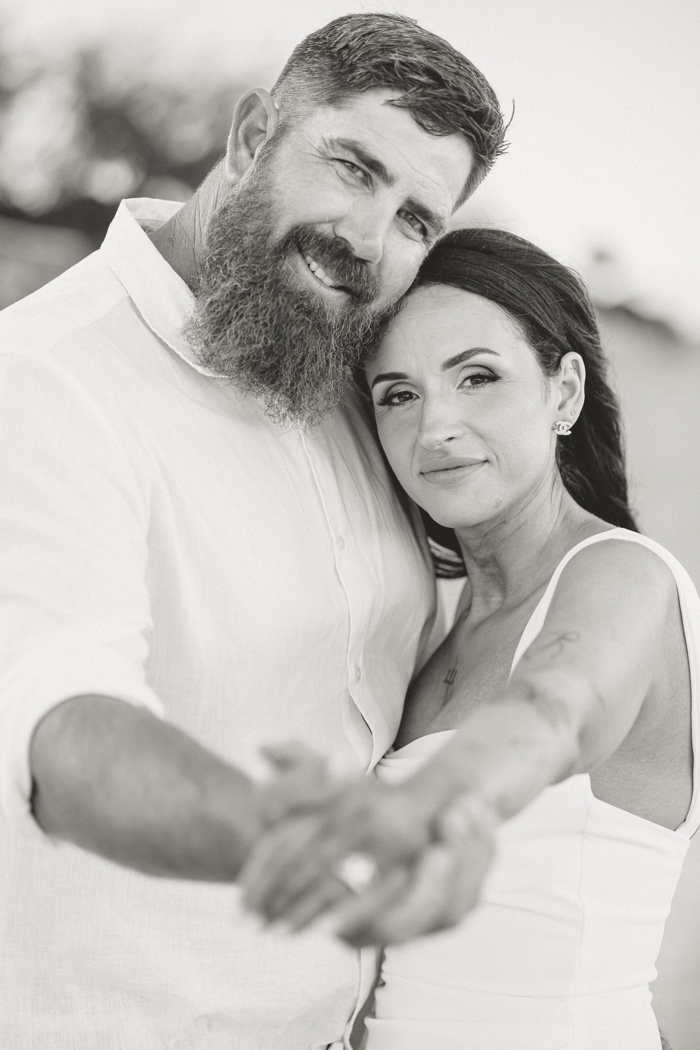 A romantic black and white portrait series of a couple embracing and smiling together outdoors.