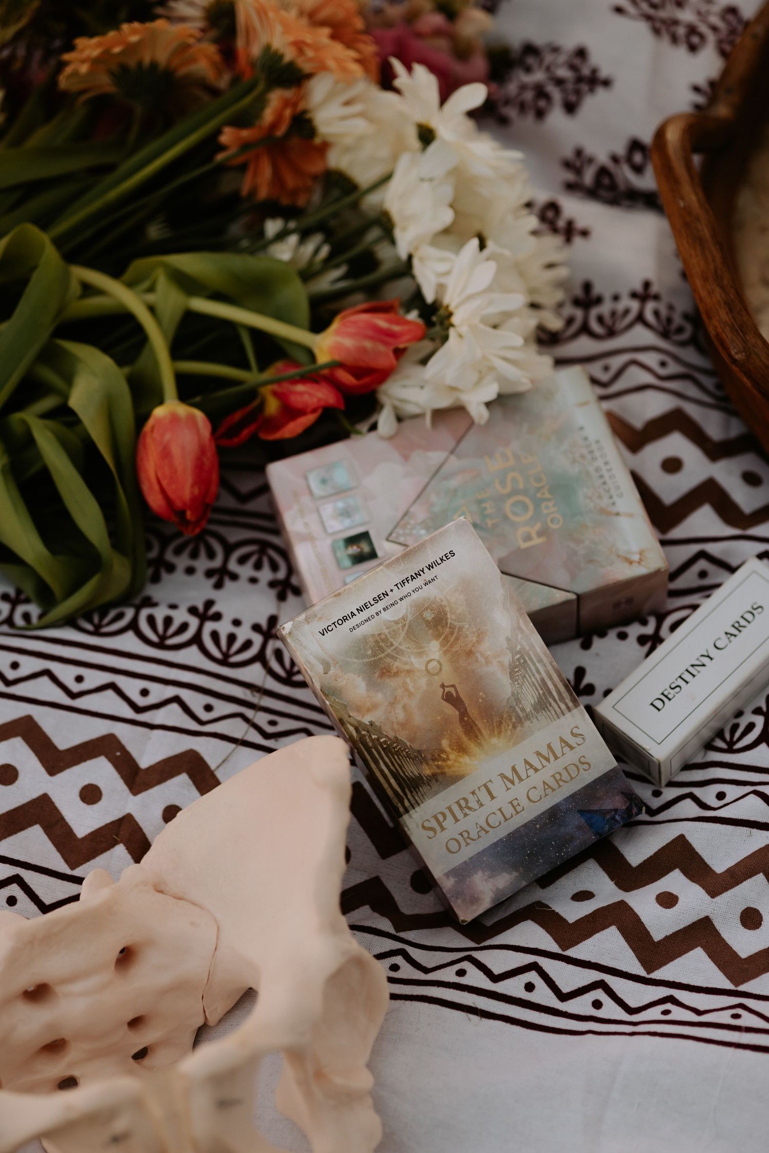 Spirit Mama Oracle Cards and Destiny Cards deck displayed on patterned cloth with fresh tulips and white flowers.
