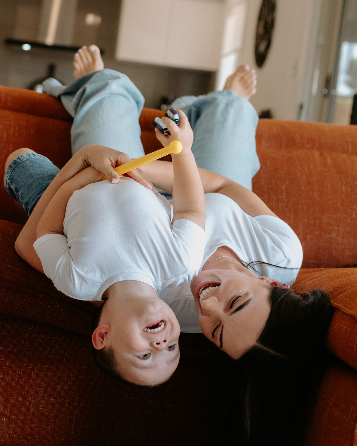 A series of photos showing someone lying on an orange couch laughing joyfully in a casual indoor setting.