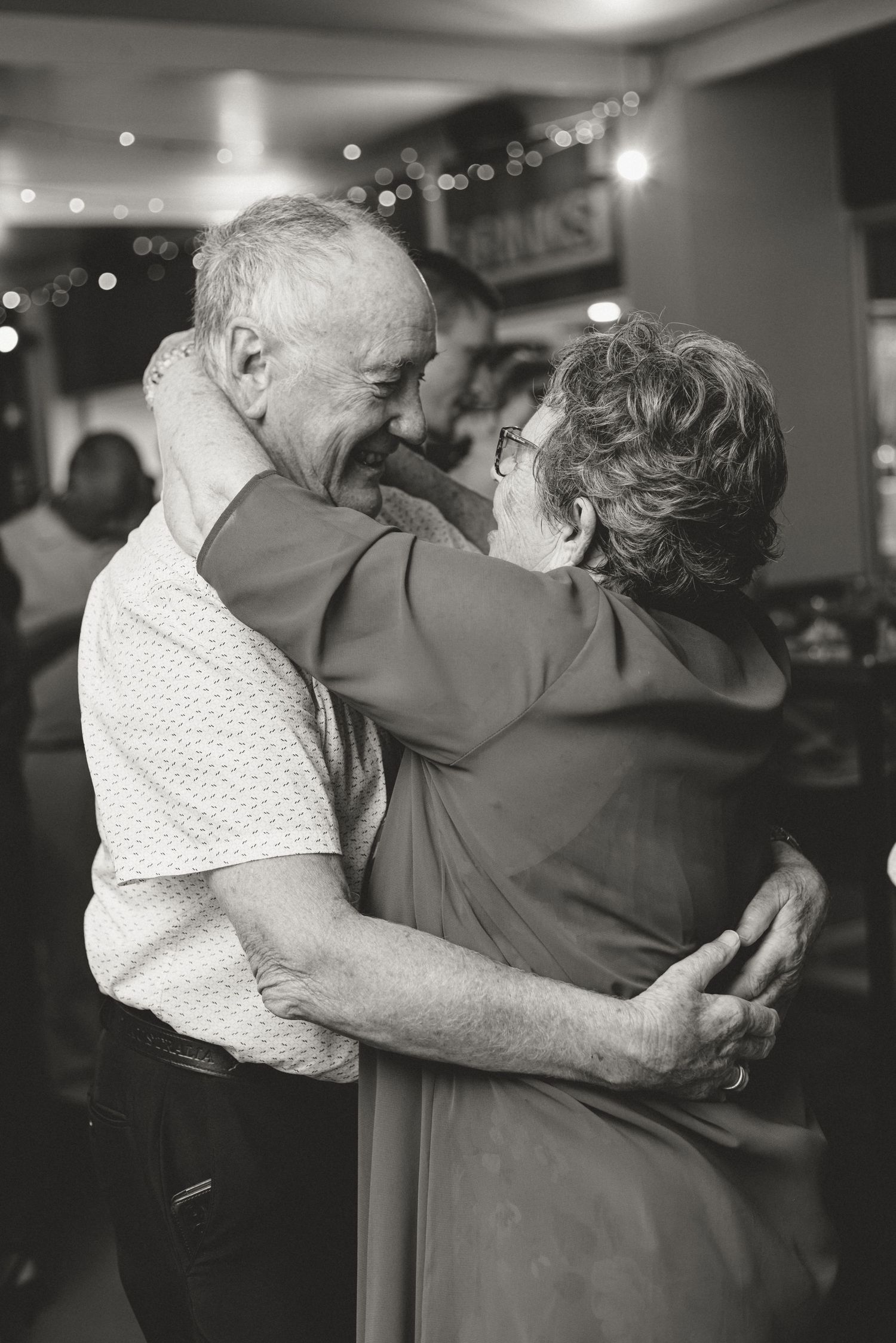 A black and white photo series showing a couple dancing together in an intimate embrace at an indoor venue.