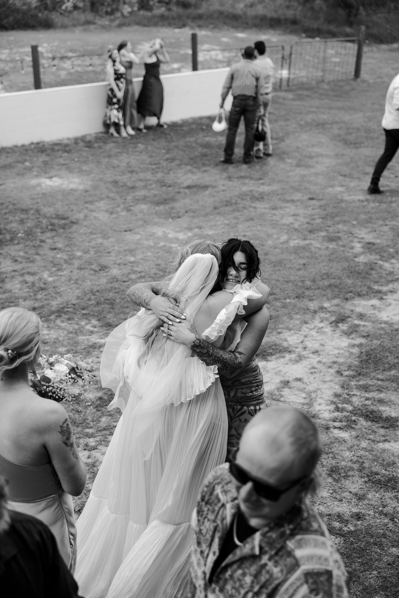 Bride receives warm embraces from guests in a heartfelt outdoor wedding celebration captured in black and white.