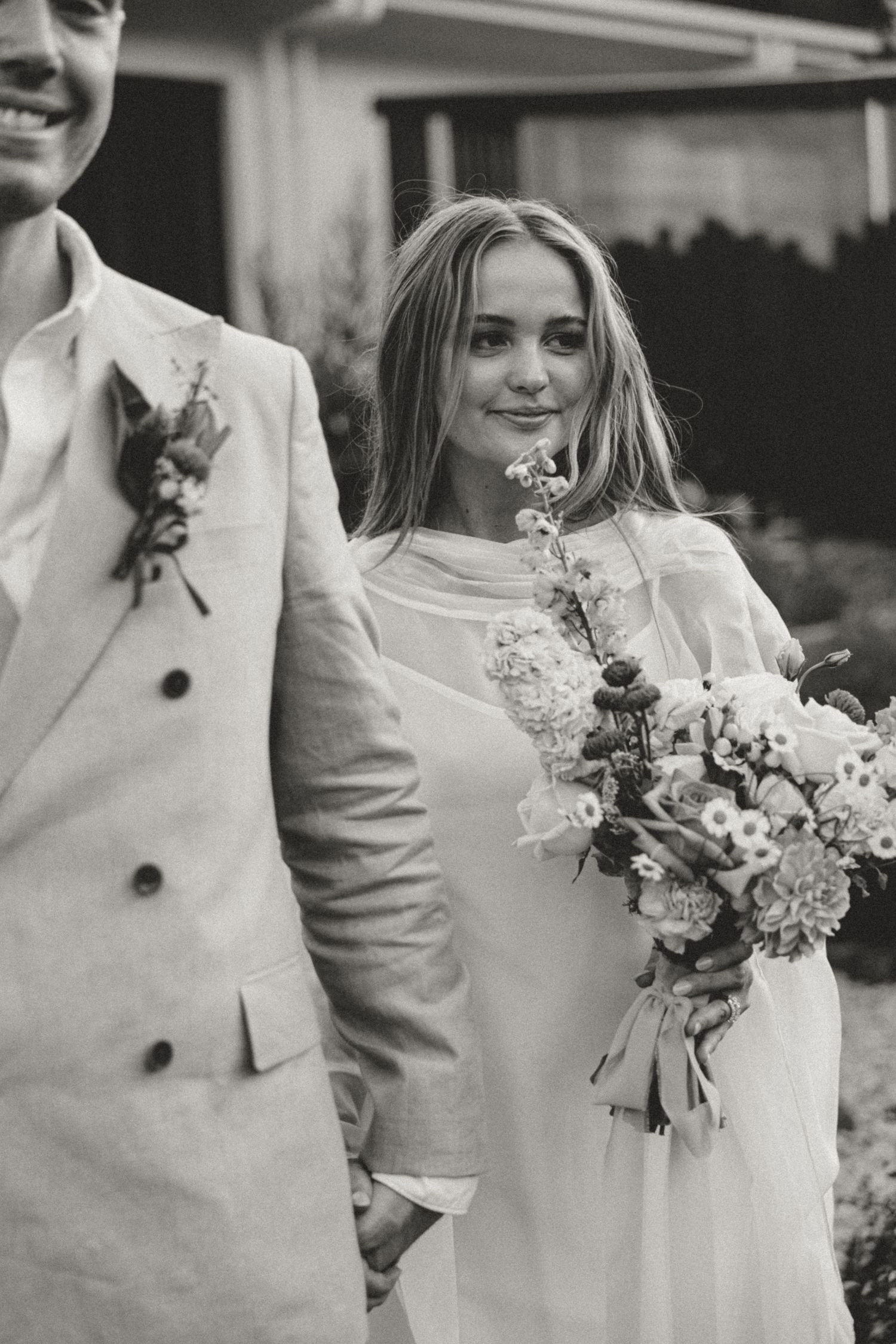 Black and white photo of a couple in formal attire holding a floral bouquet.