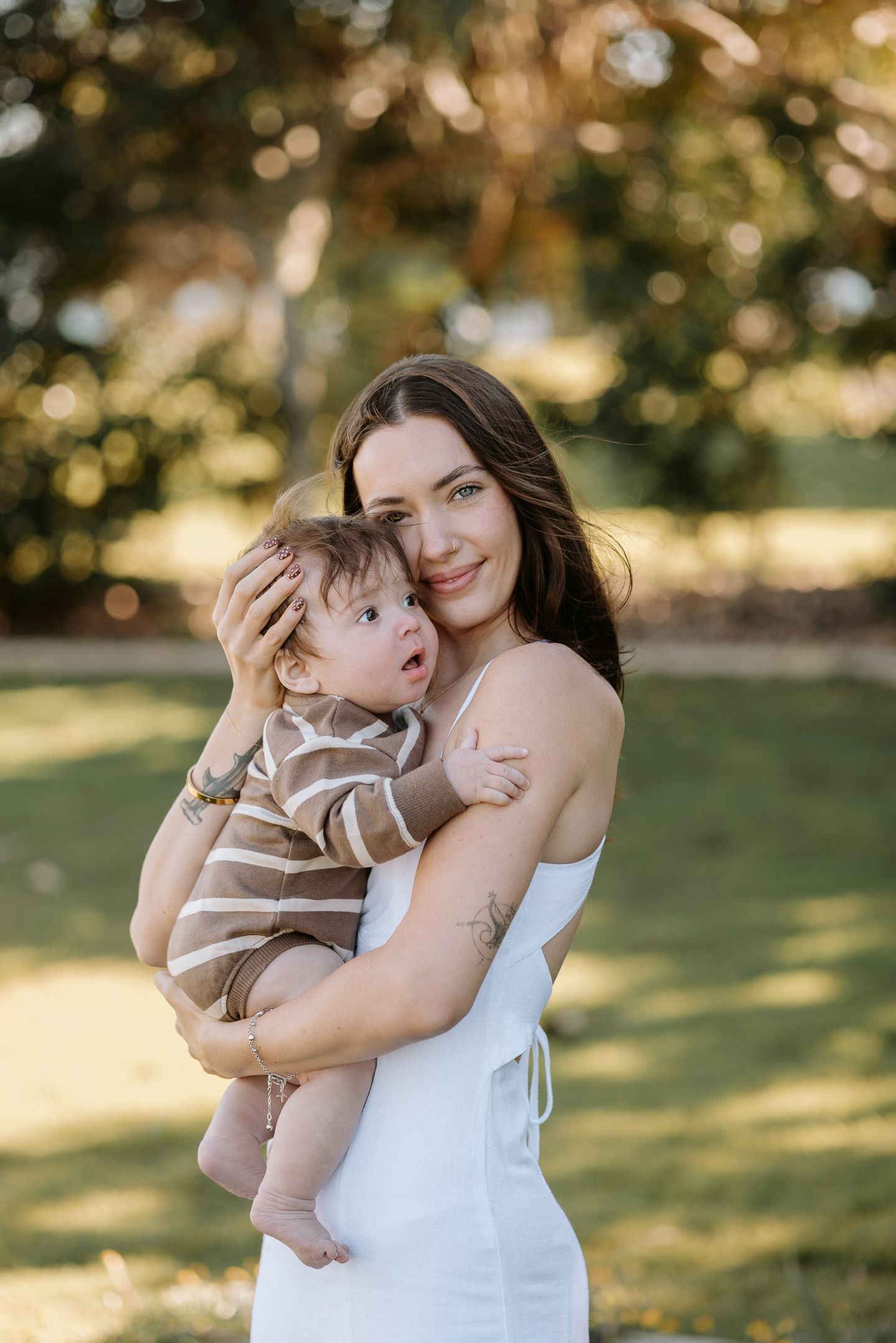 A tender outdoor portrait of a parent and child embracing in golden sunlight.