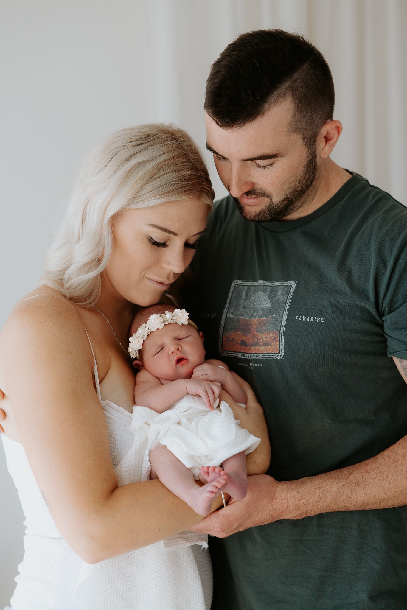 A series of intimate family photos showing parents tenderly holding and bonding with their newborn baby in white.