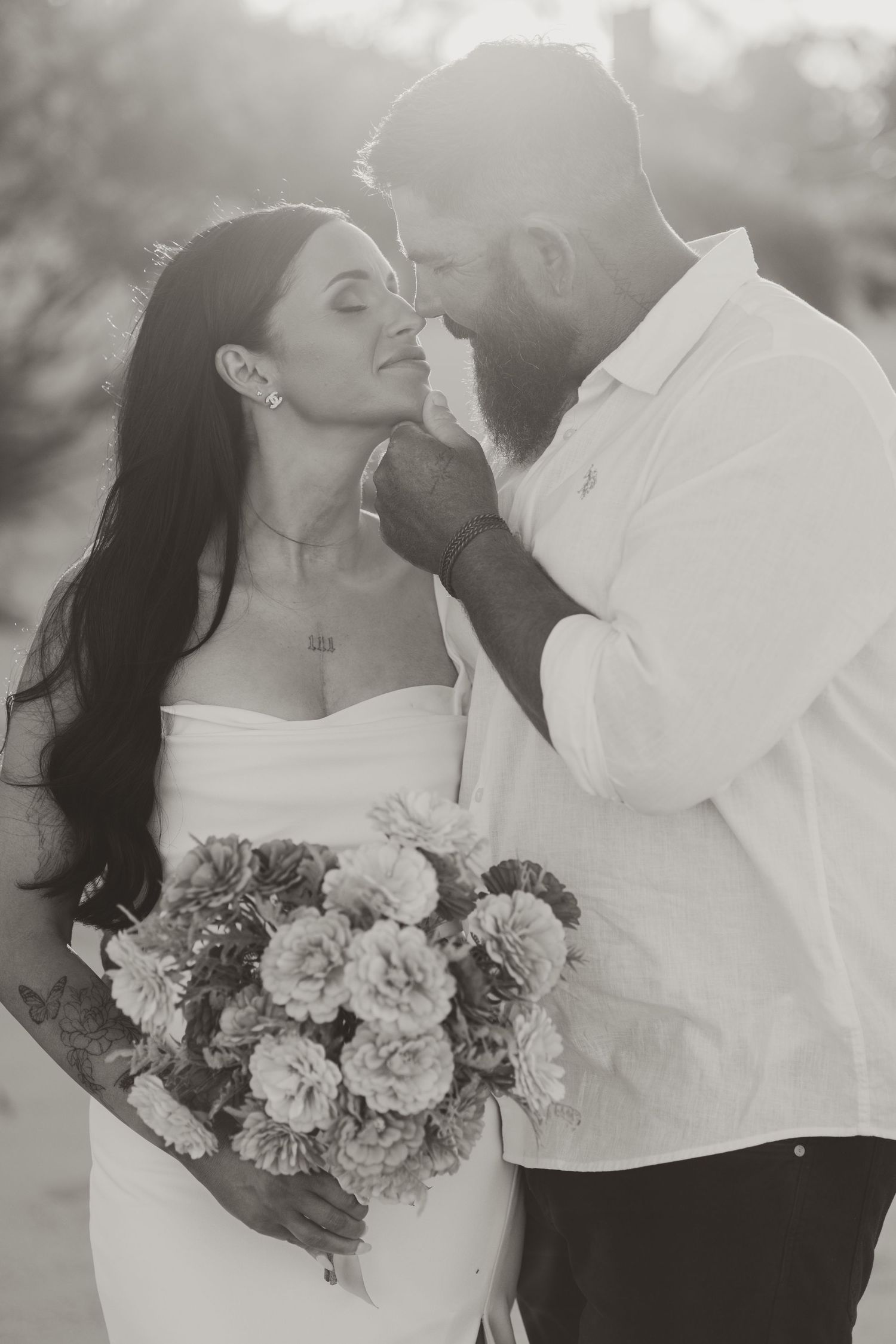 Black and white portrait of a couple sharing an intimate moment with a bouquet.