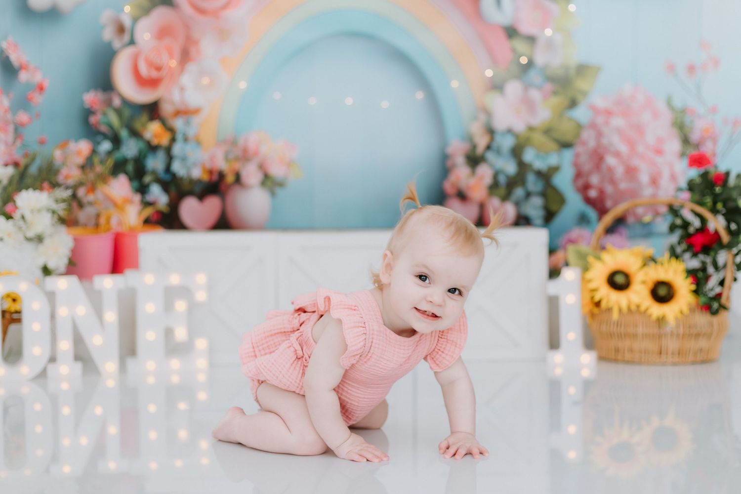 Floral themed baby photo collage with pink and blue tones featuring milestone moments against pastel backdrops.