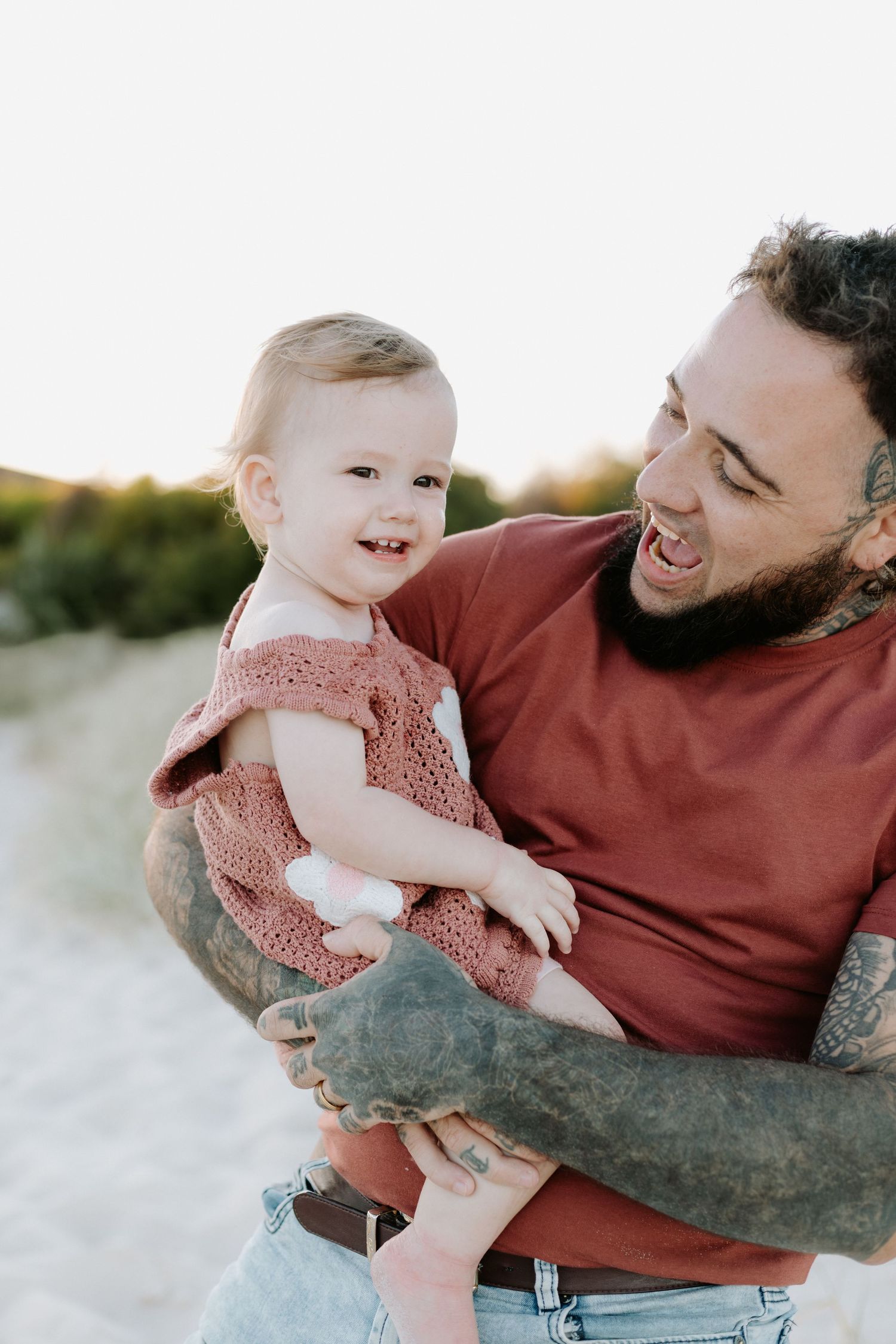 A heartwarming series of candid moments between a parent and baby playing together on a sandy beach at sunset.