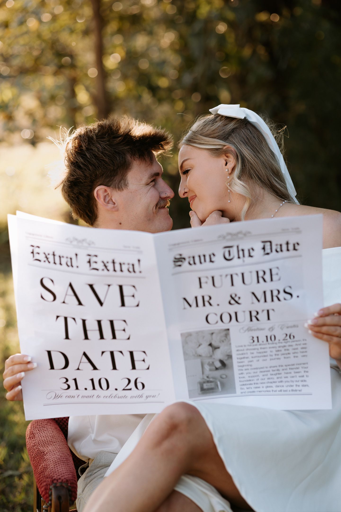 Couple holding a newspaper-style Save the Date for Future Mr. & Mrs. Court, dated 31.10.26, sharing a romantic moment.