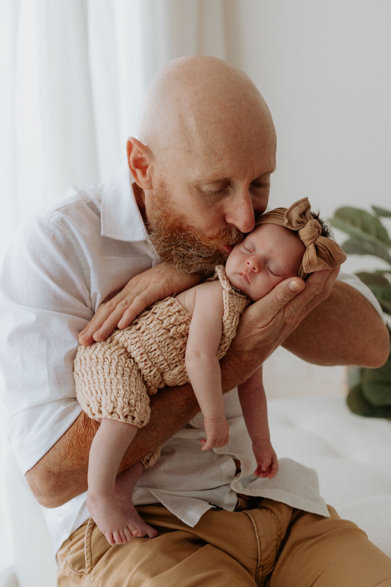 Sweet moment showing tender interaction between parent and baby in soft white natural light setting.