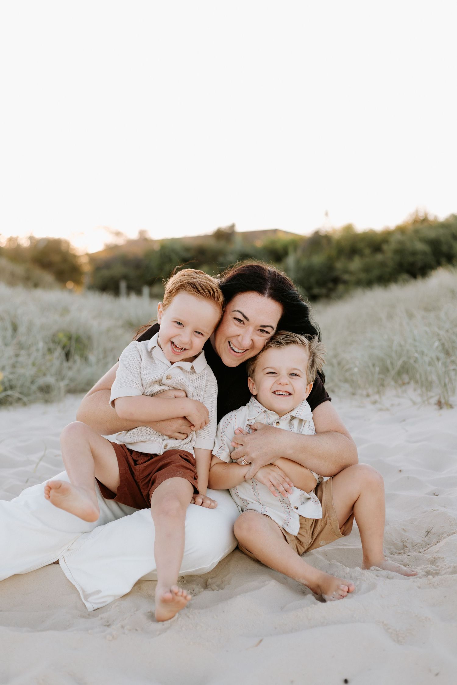 A joyful family moment captured on a sandy beach at sunset with natural light and warm expressions.