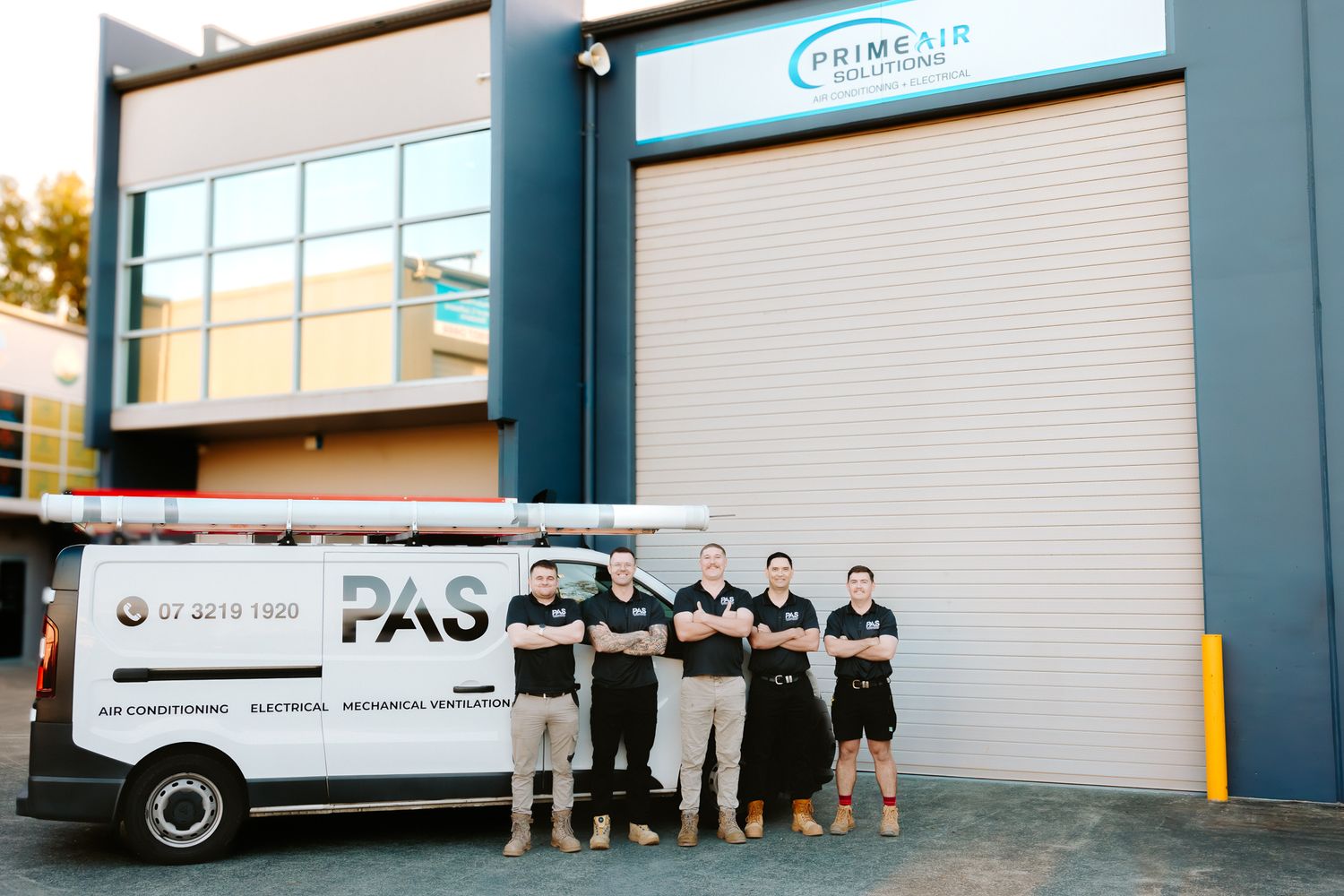 PrimAir Solutions team of four technicians standing in front of their branded PAS van outside their commercial headquarters.