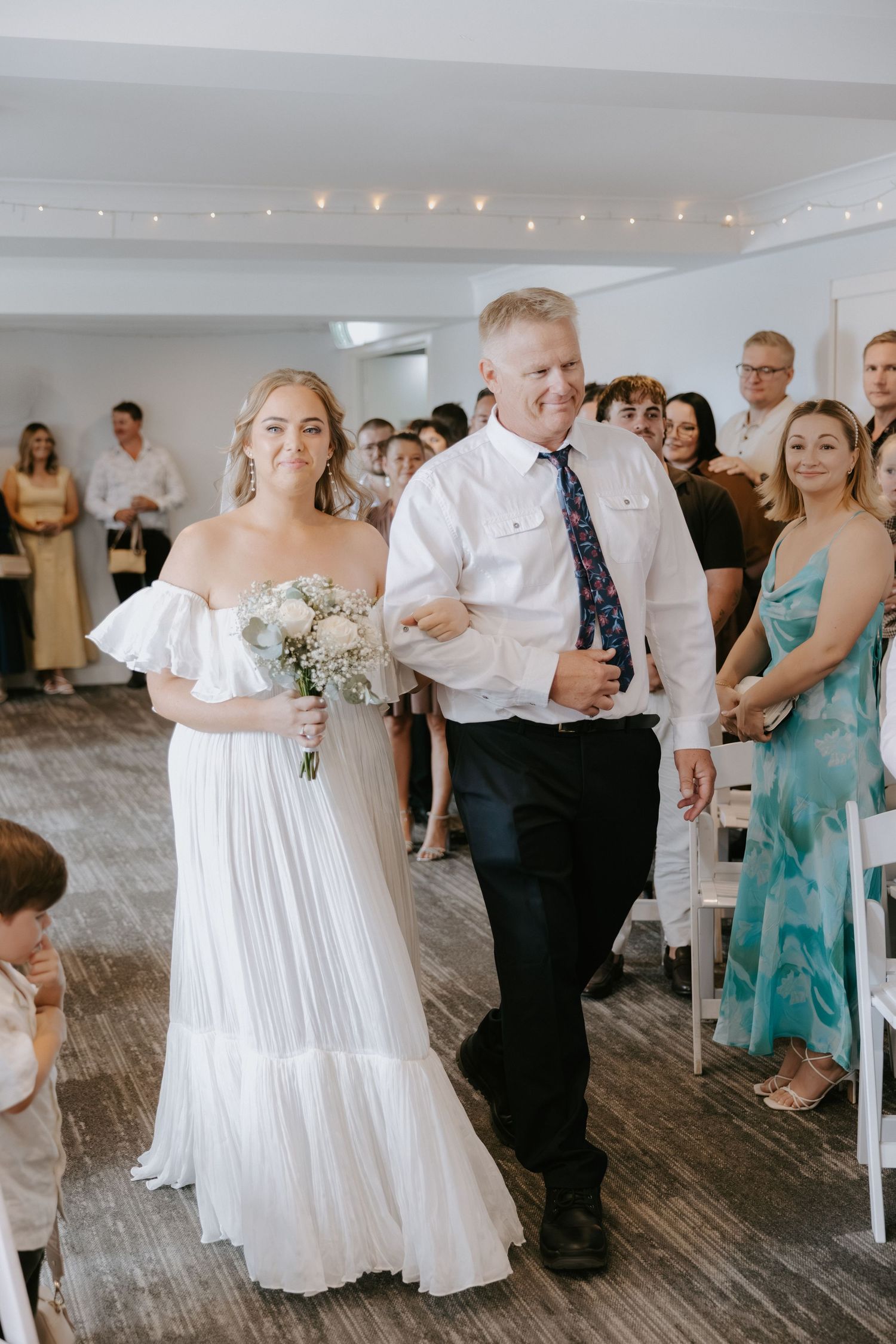 Wedding guests dance together on a rustic wooden floor under string lights during a reception celebration.