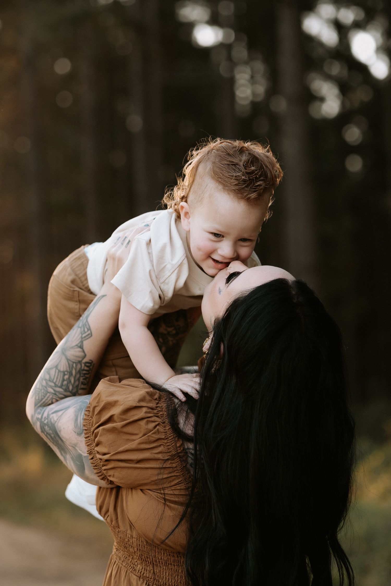 A tender moment shared between parent and child playing together outdoors in a wooded setting.