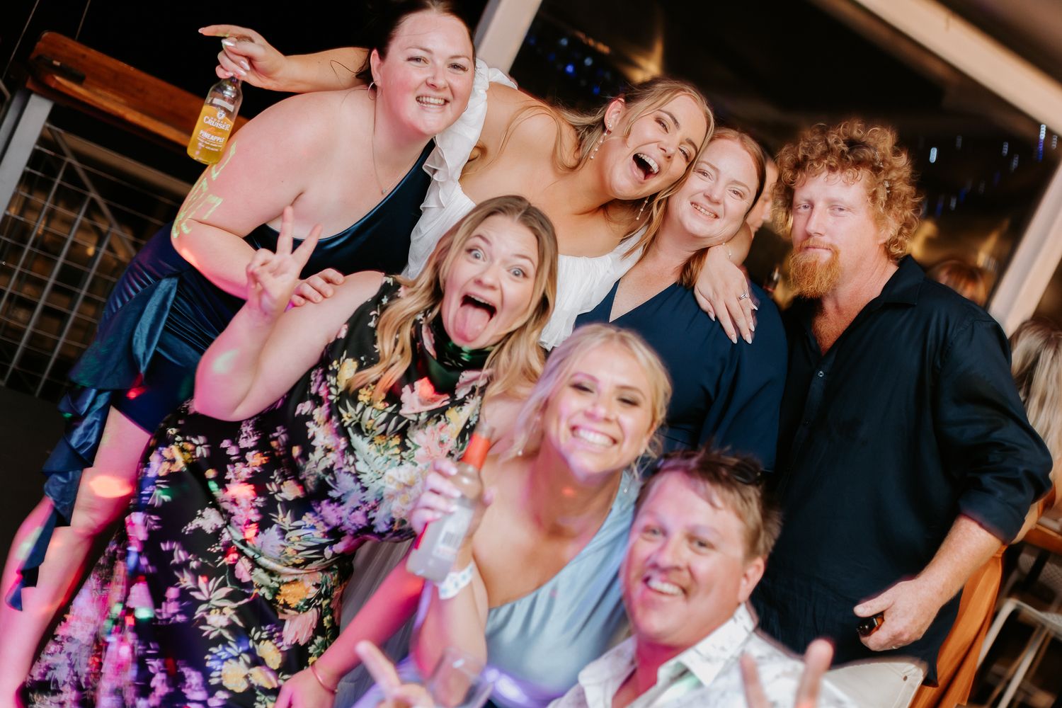 Group of joyful wedding guests posing and celebrating together at a lively wedding reception.