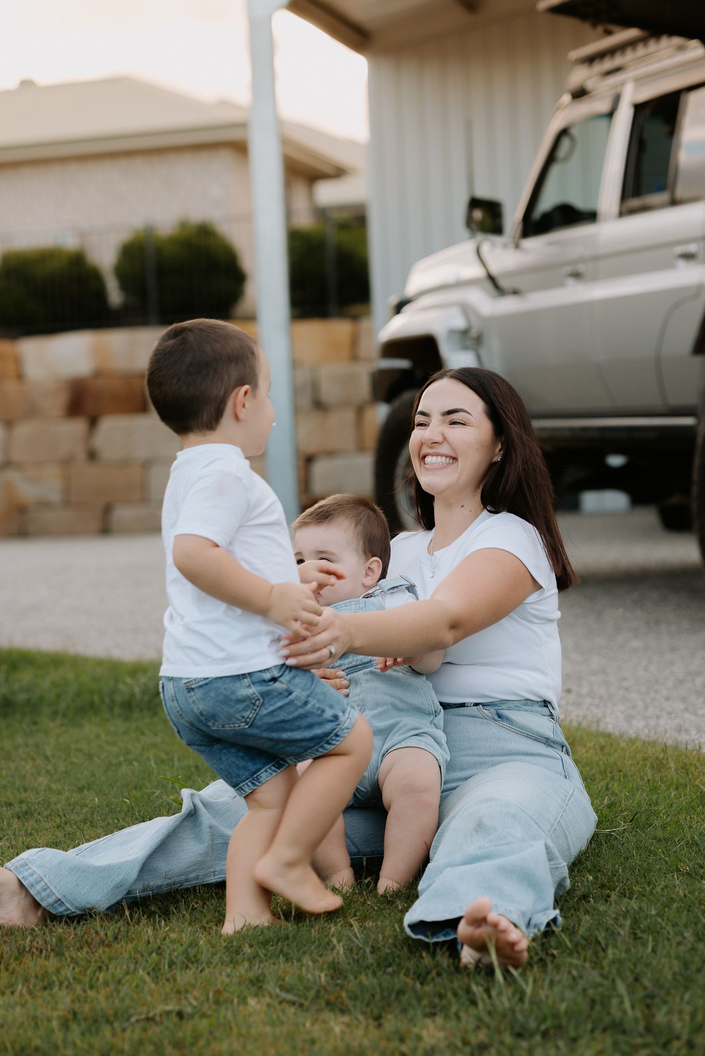 A playful sequence of candid moments between parent and child sitting together on grass near a building.