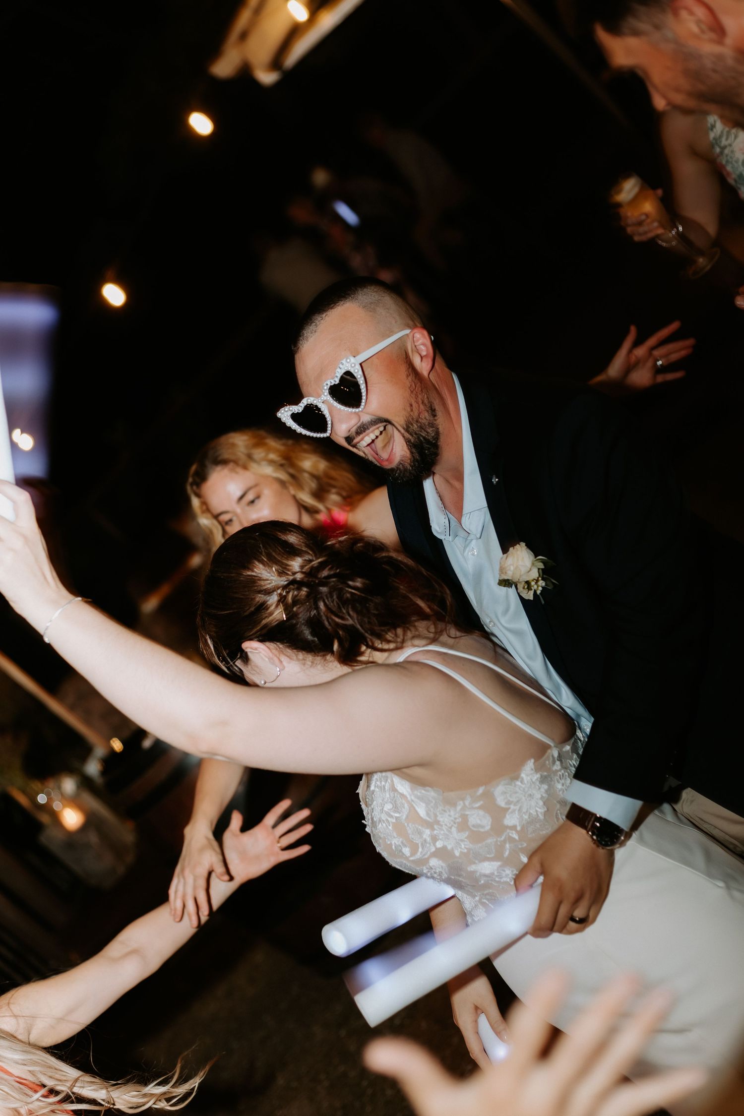 Dynamic dance floor moment captured at nighttime wedding reception.