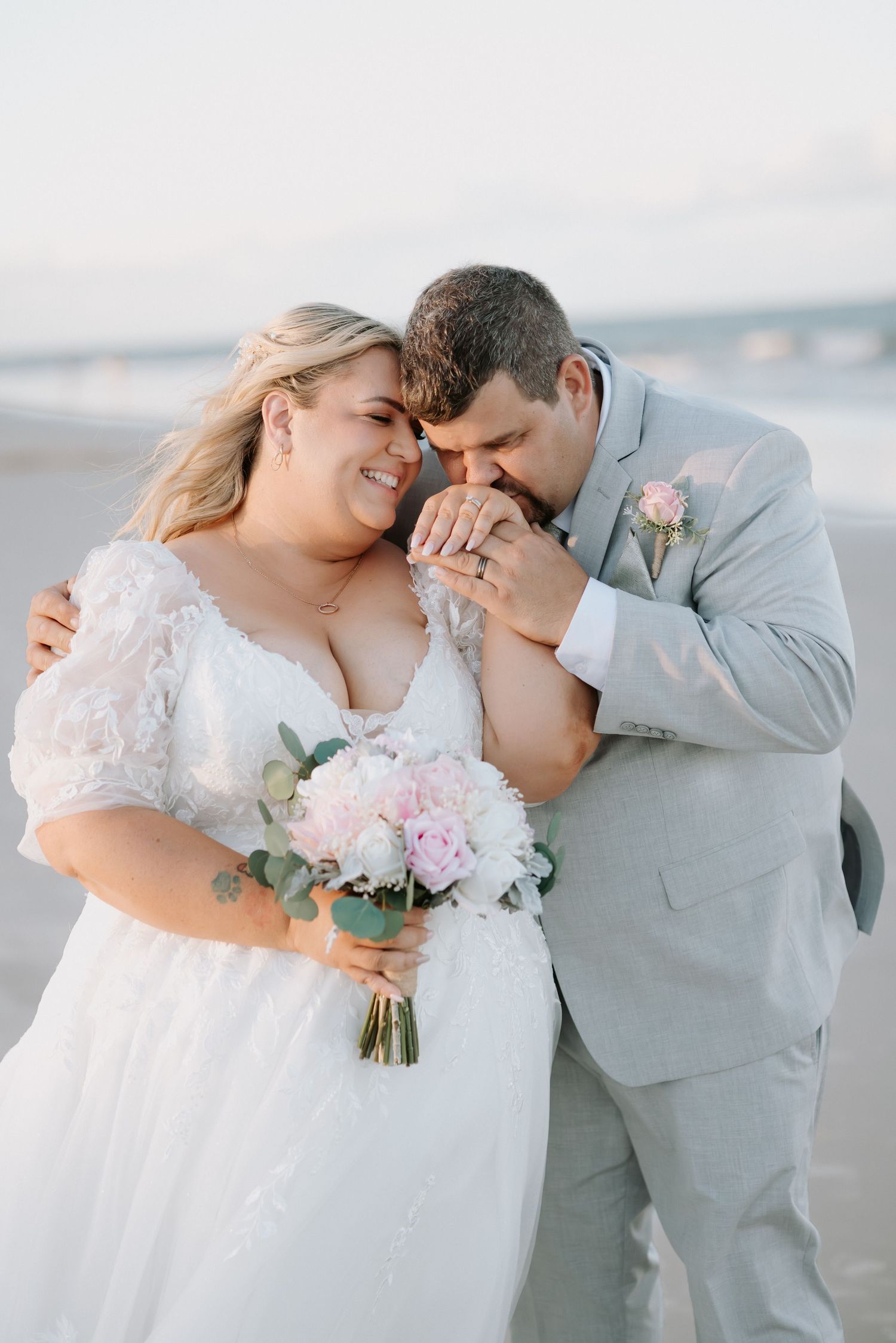 A tender moment between newlyweds on a beach with soft lighting.