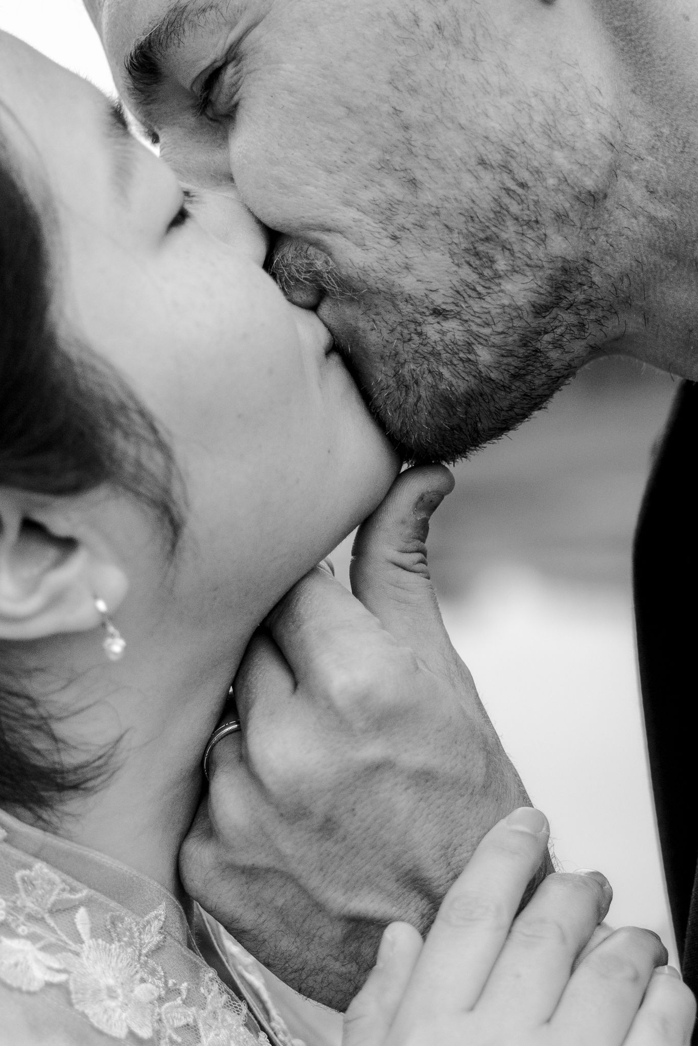 Black and white close-up of a couple sharing a romantic kiss, with the man gently holding the woman's chin.