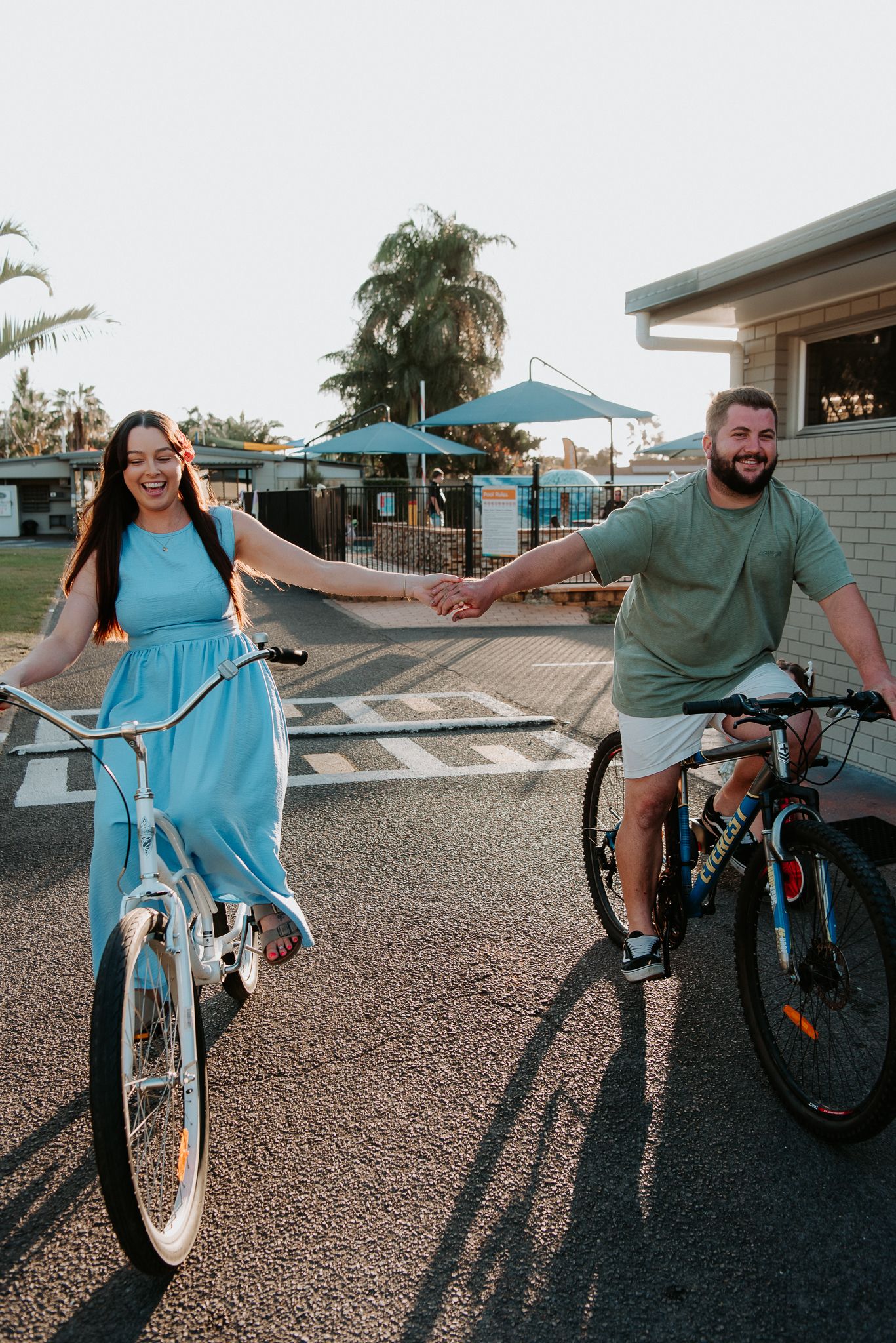 A playful sequence of photos showing two people having fun riding bikes together in a parking lot on a sunny day.