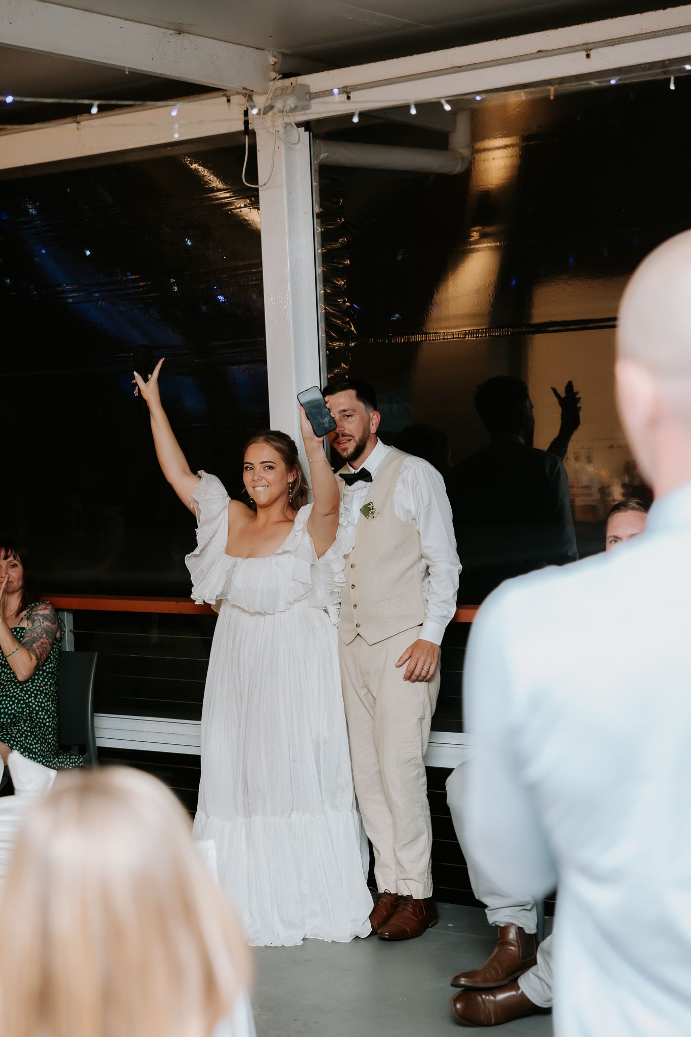 Bride and groom making grand entrance at wedding reception, bride raising hand in celebration.