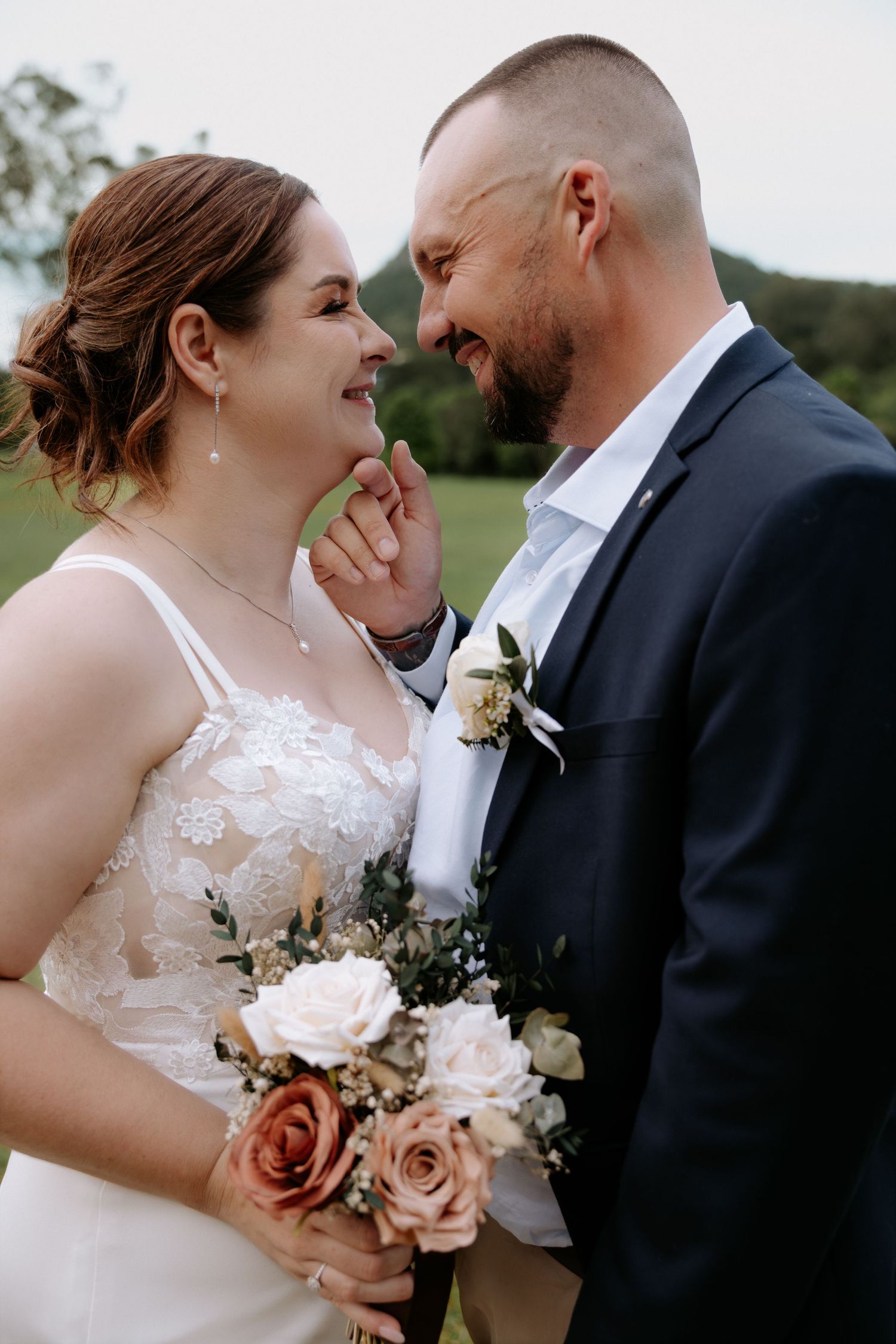 Intimate wedding couple portrait with soft pink roses and natural lighting.