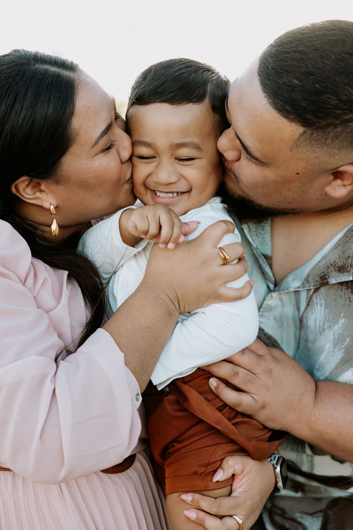 A series of loving family photos showing parents kissing their child in sequence.