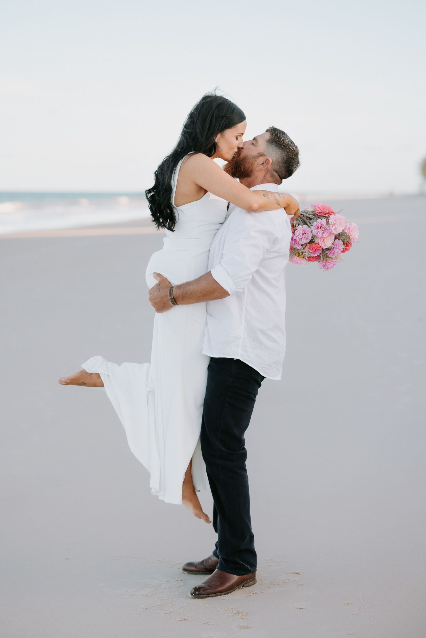 A romantic couple in white and black attire share intimate moments in a sequence of beach photos.