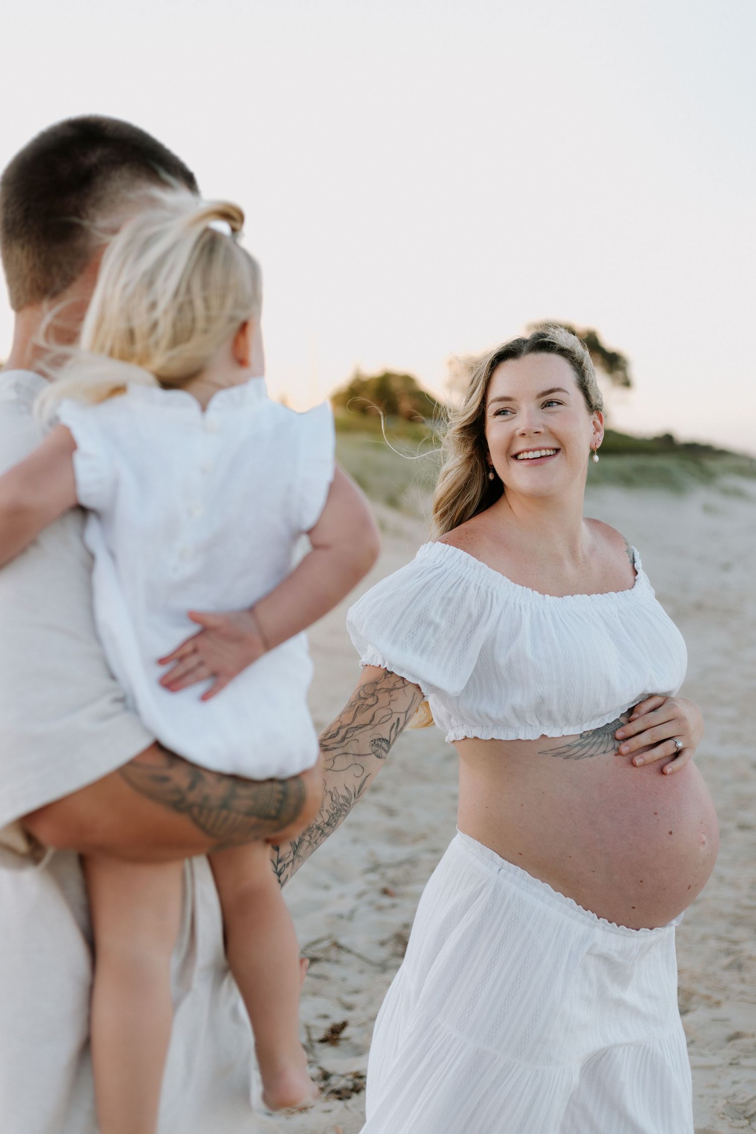 A series of candid beach photos showing tender moments between people wearing white clothing on a sandy shore.