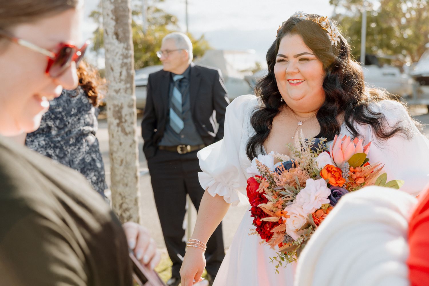 Wedding party celebrating outdoors with autumn-colored floral bouquets and decorations.
