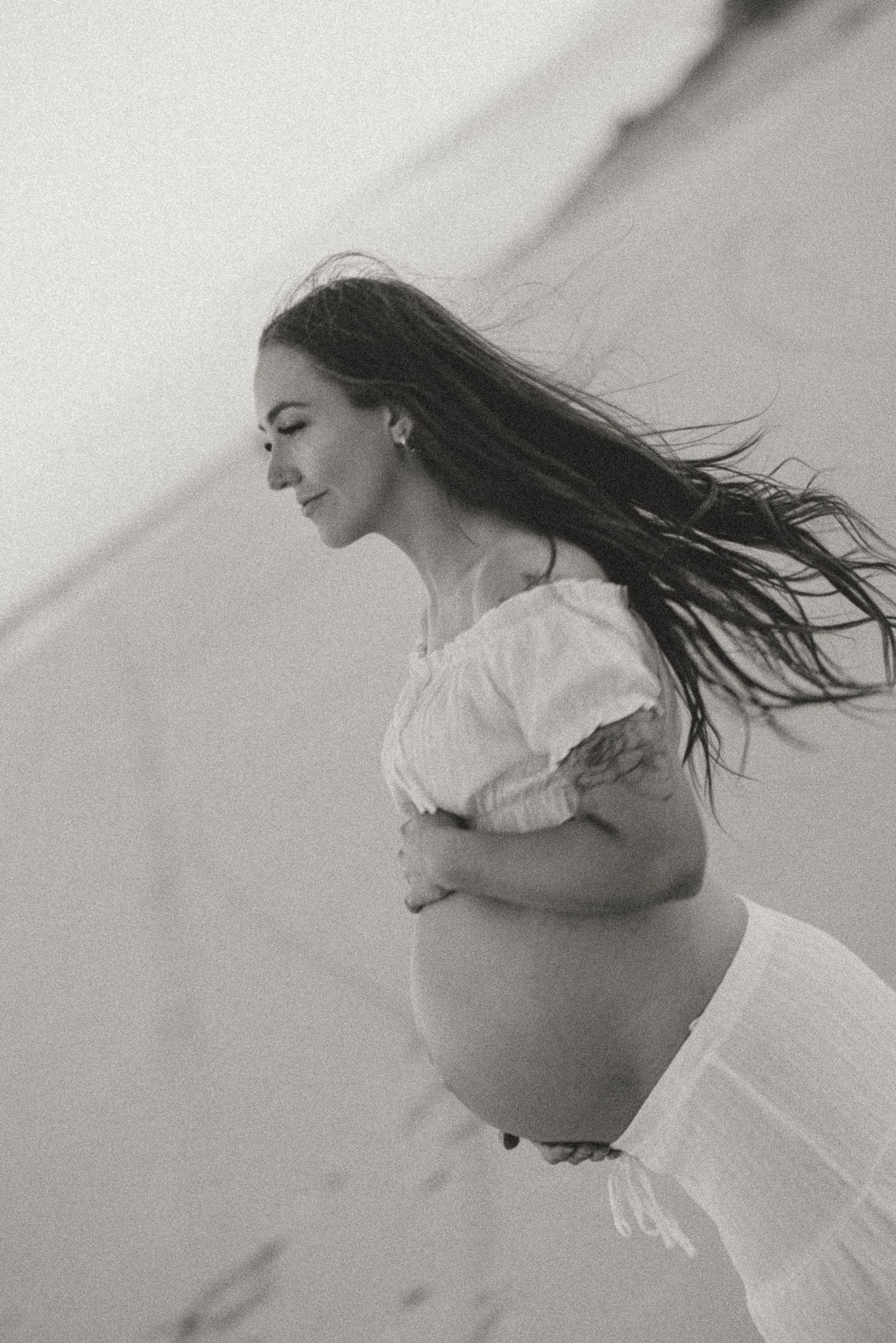Black and white artistic sequence showing a figure in white clothing with flowing hair in graceful motion.