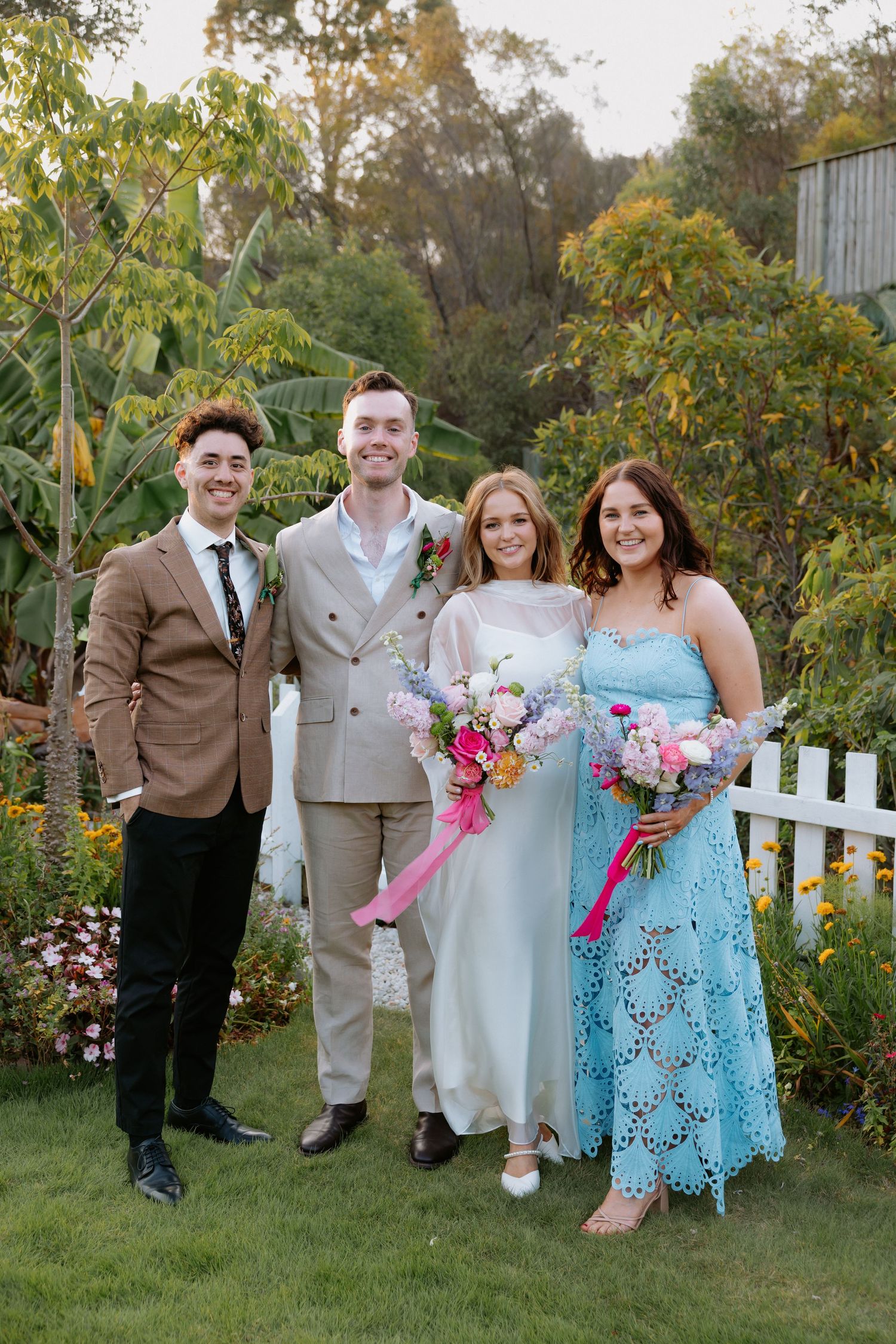 A group poses together in a garden setting with white picket fence.