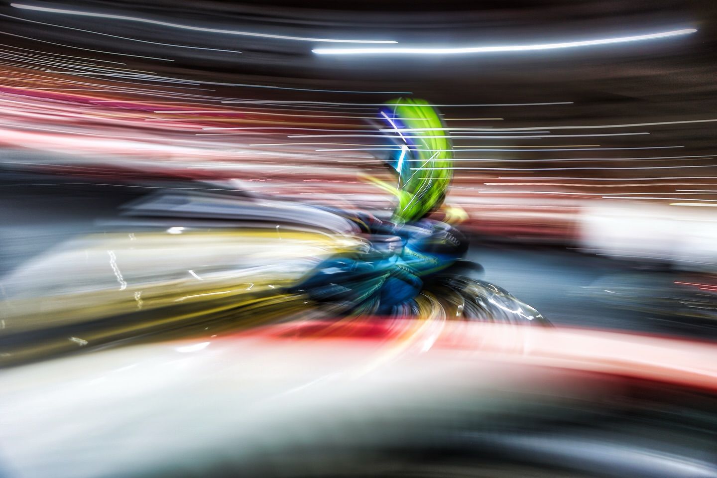 Motion blur effect creates dramatic streaks of light and color during a high-speed karting race.