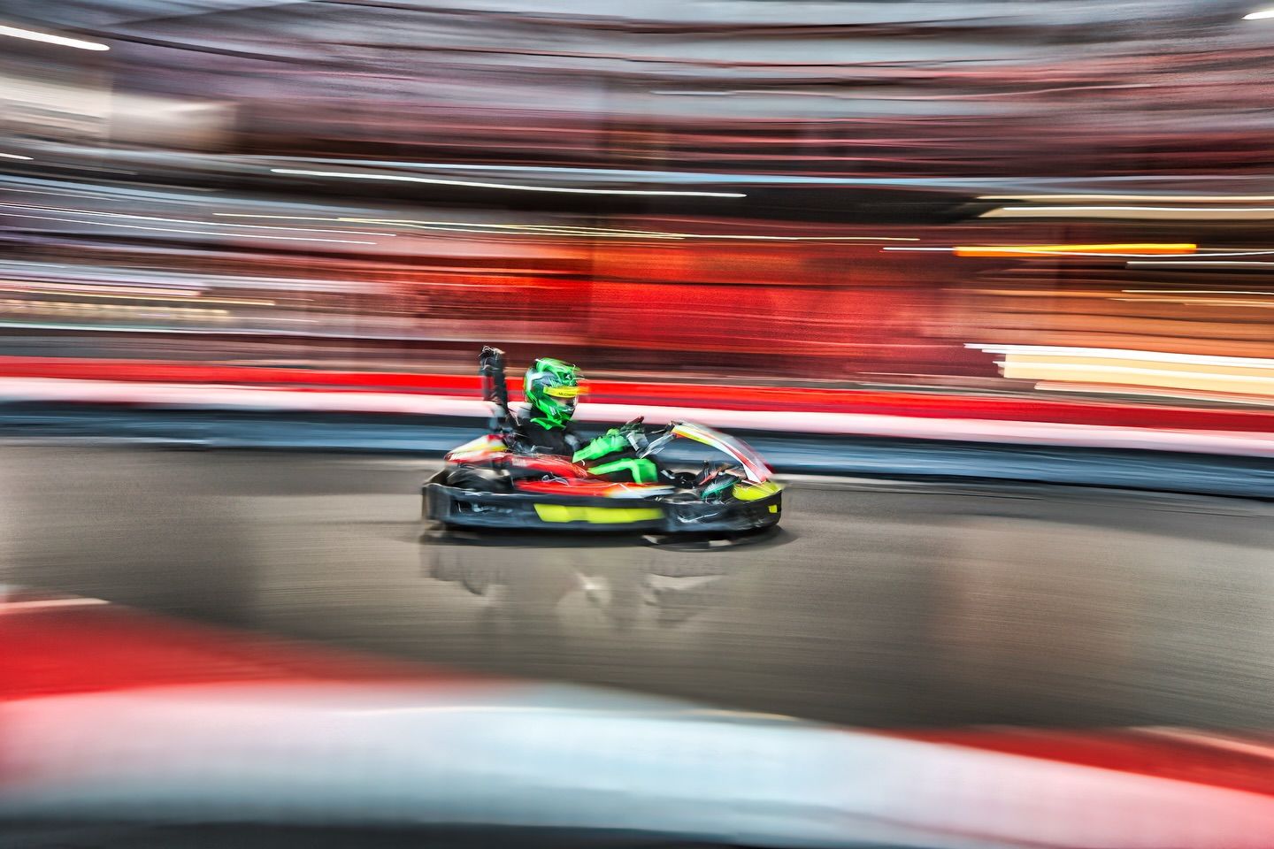 Motion-blurred go-karts racing at high speed on a professional karting circuit.