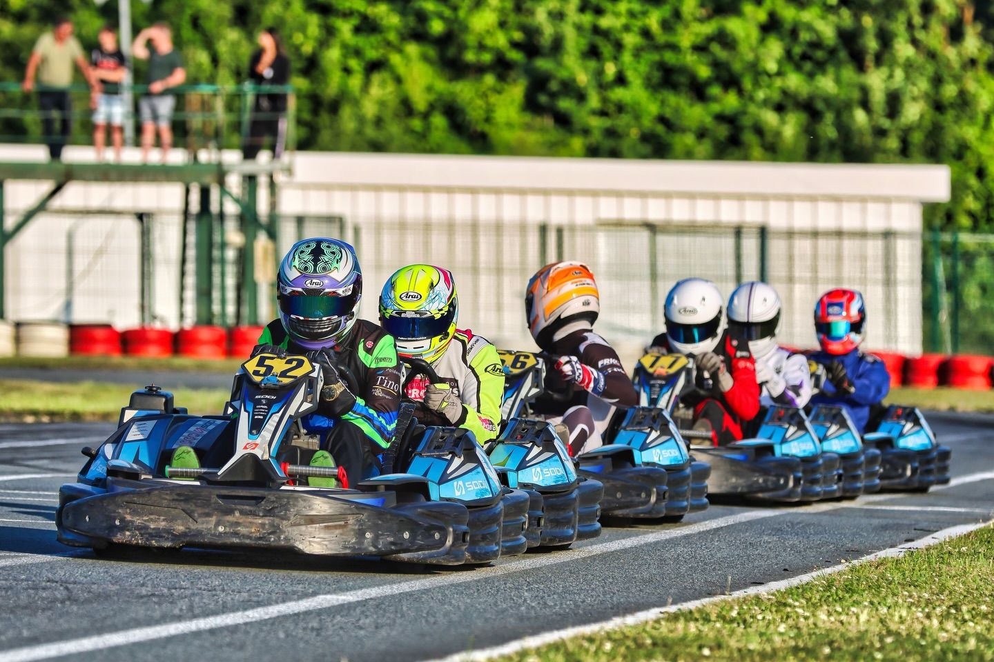 Row of colorful go-karts lined up on an outdoor racing track.