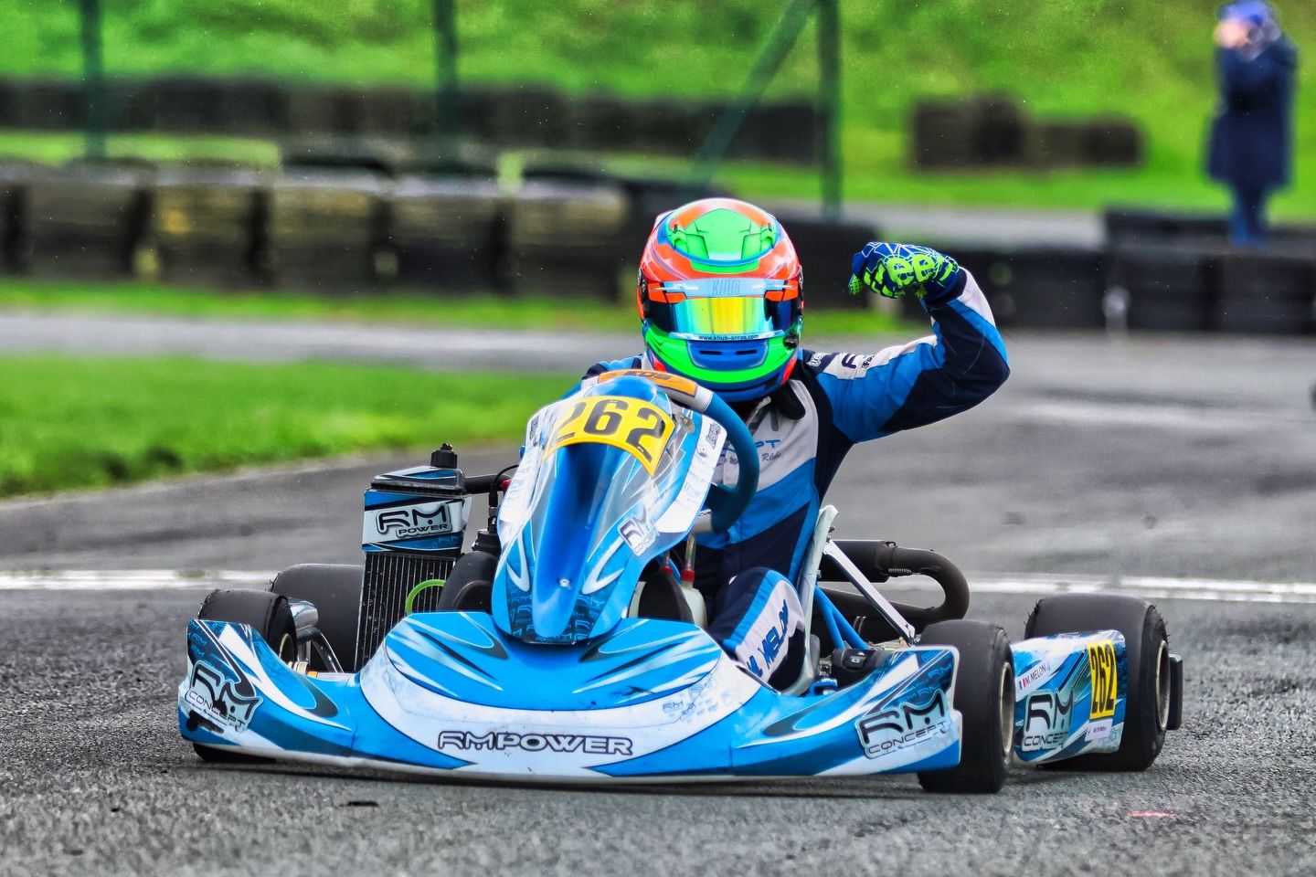 Blue go-kart navigating through a corner on an outdoor karting track.