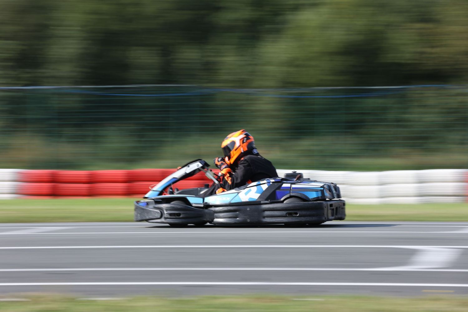 Go-kart racing at high speed captured with motion blur on outdoor track.