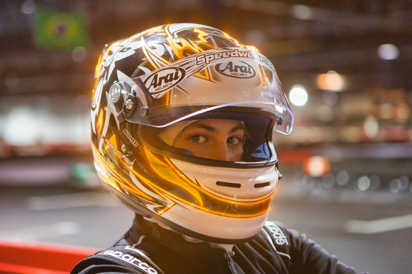 Close-up of a gold-colored racing helmet with decorative designs.