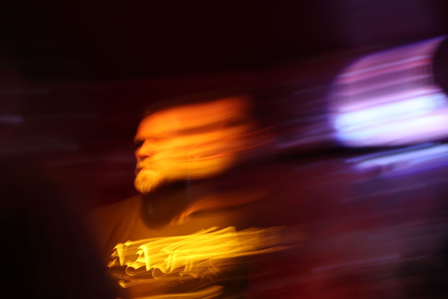 Abstract light trails in orange and purple creating artistic motion blur effect.
