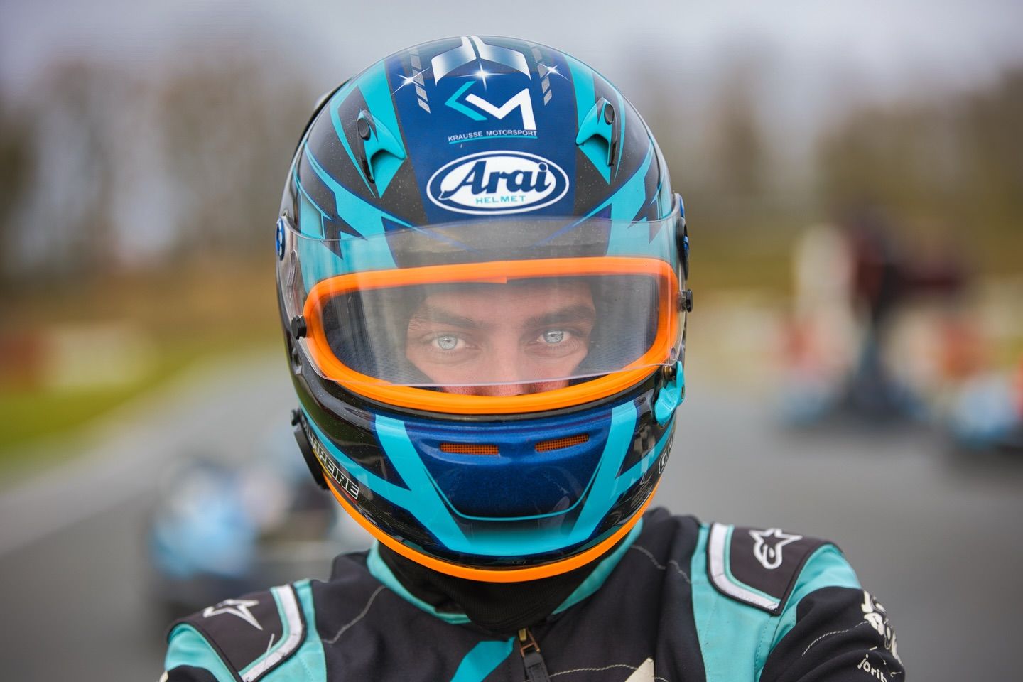 Racing drivers in colorful helmets preparing for competition on the track.