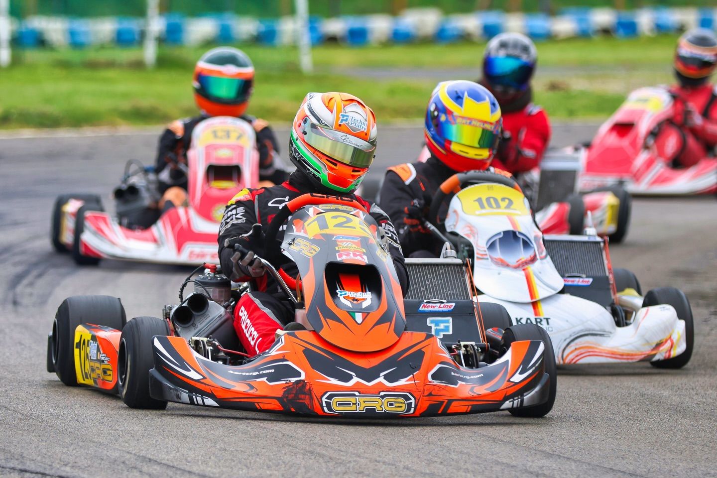 Go-karts racing around a track with colorful liveries competing for position.
