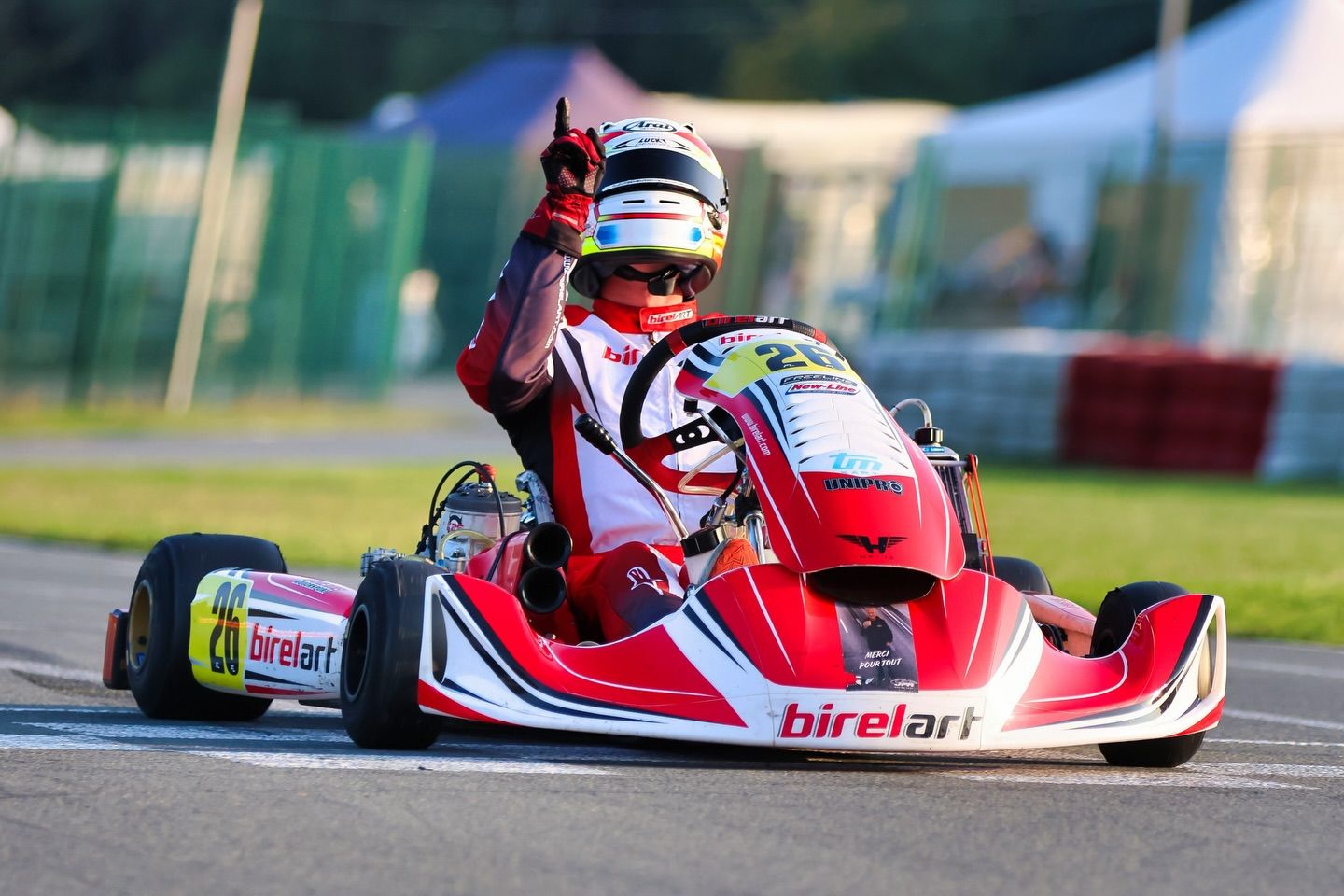 Red and white go-karts competing closely on a professional karting circuit.