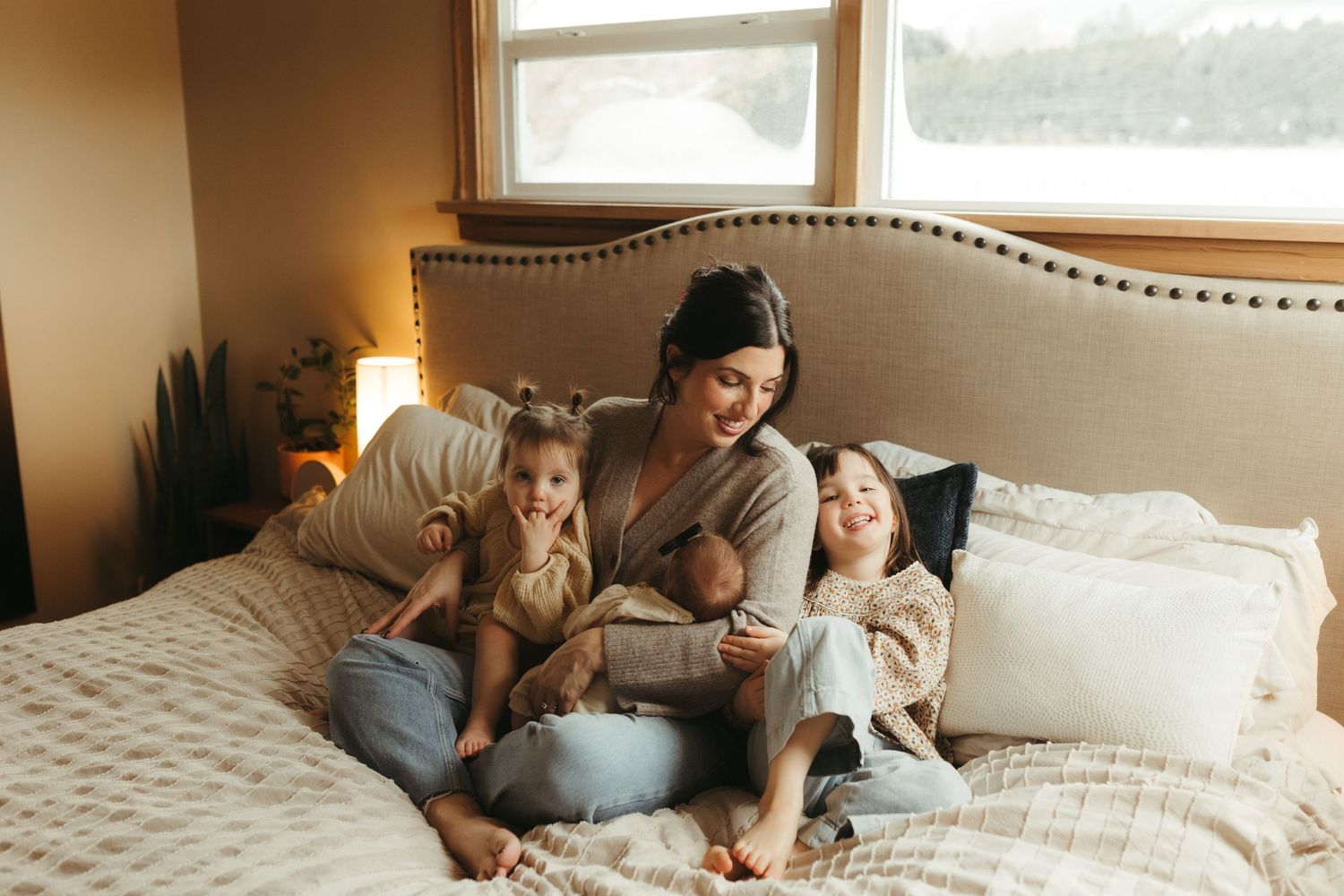 A cozy family moment reading together on a bed with natural light streaming through the window.