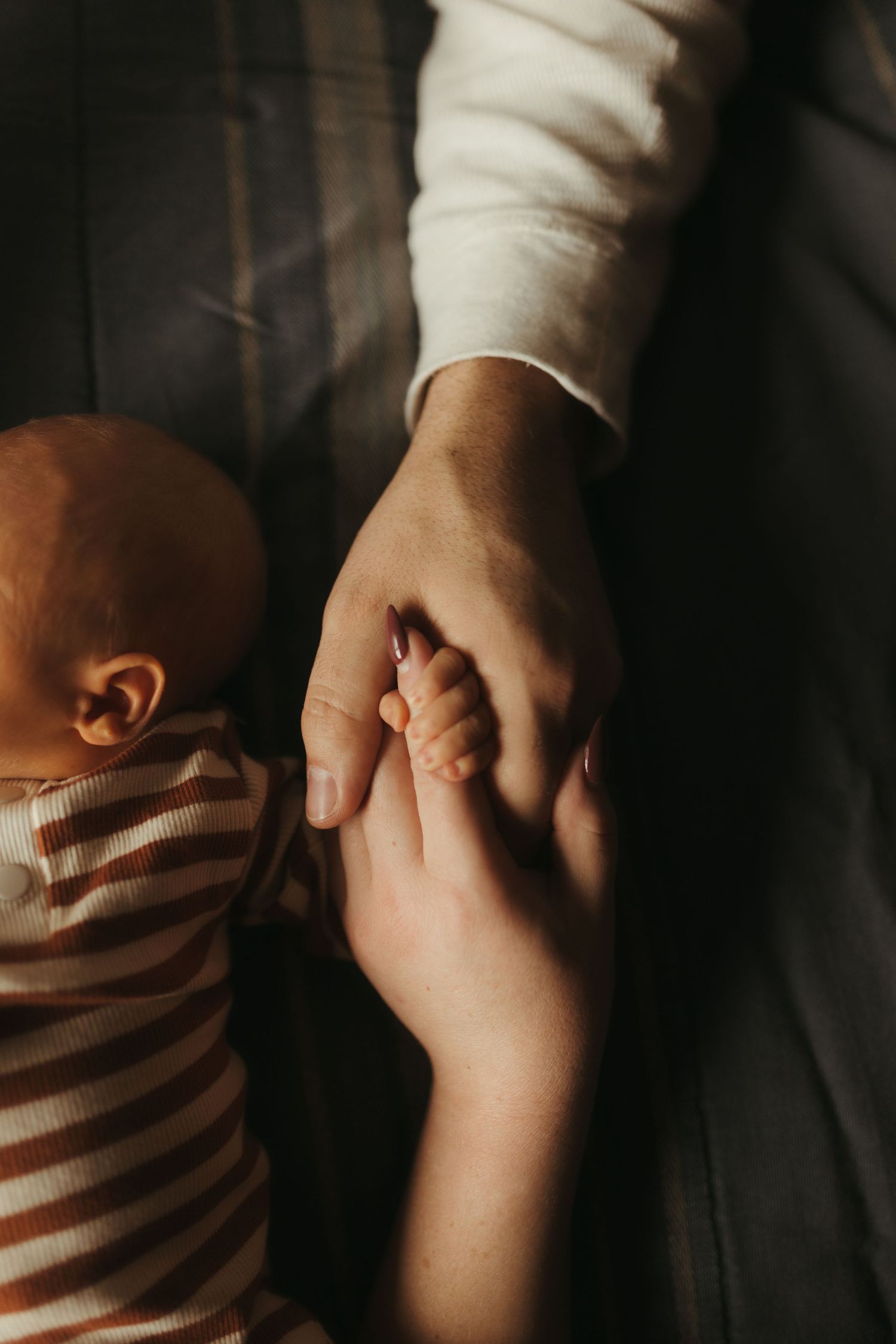 Close-up shot of two hands holding each other tenderly in soft, warm lighting.