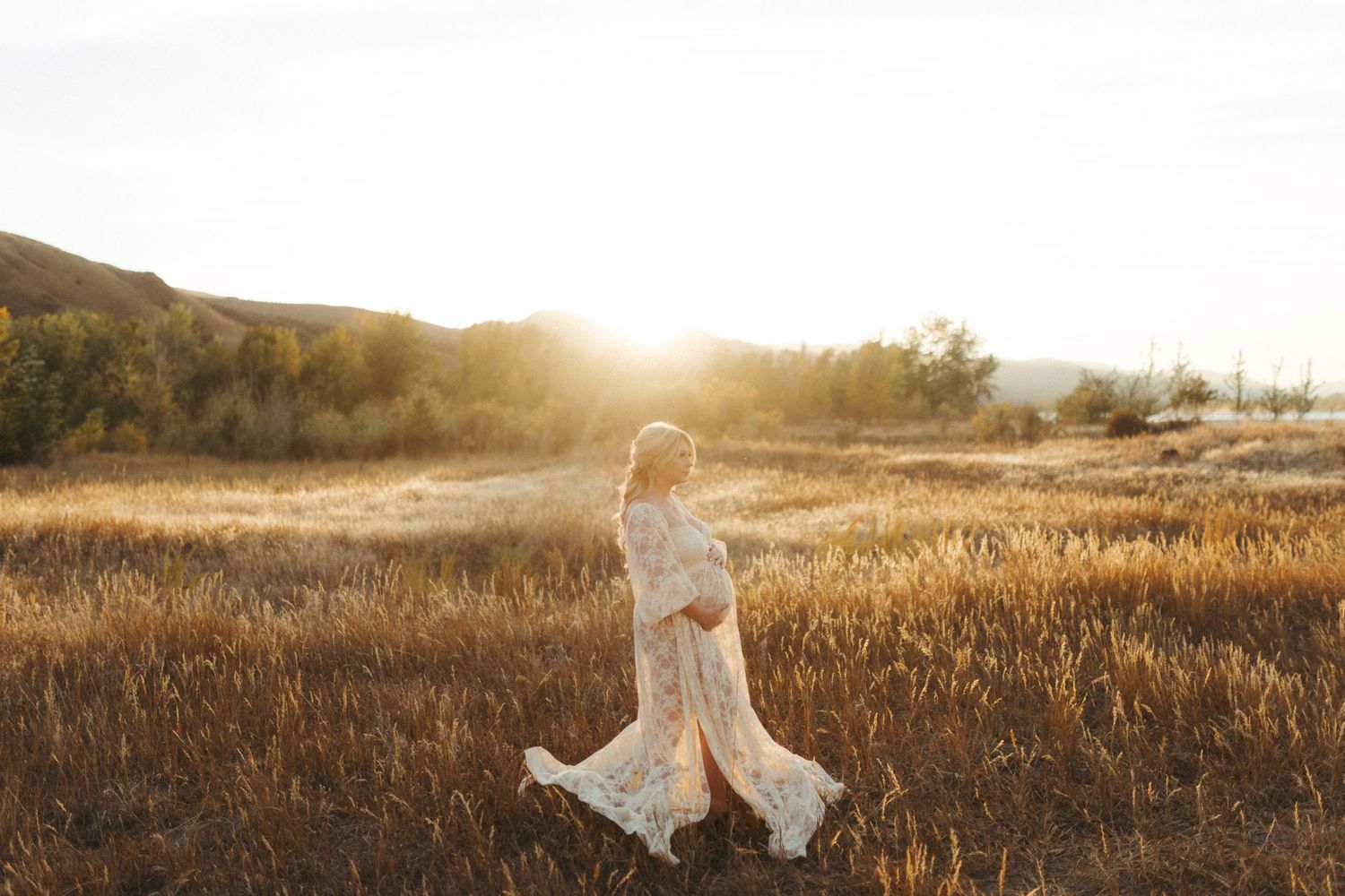 A person in a flowing white dress walks through a sunlit meadow at golden hour.