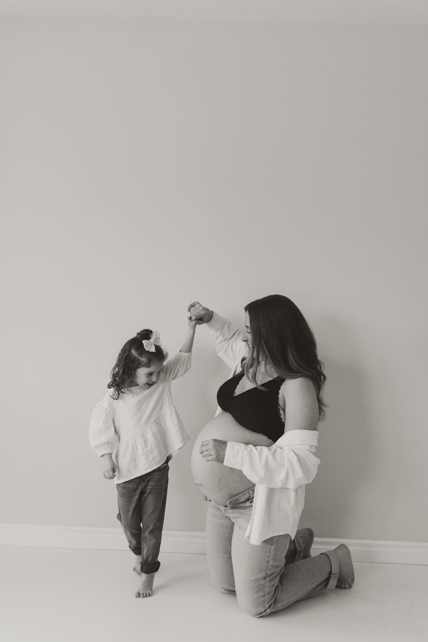 A touching moment between parent and child playing together against a white wall.