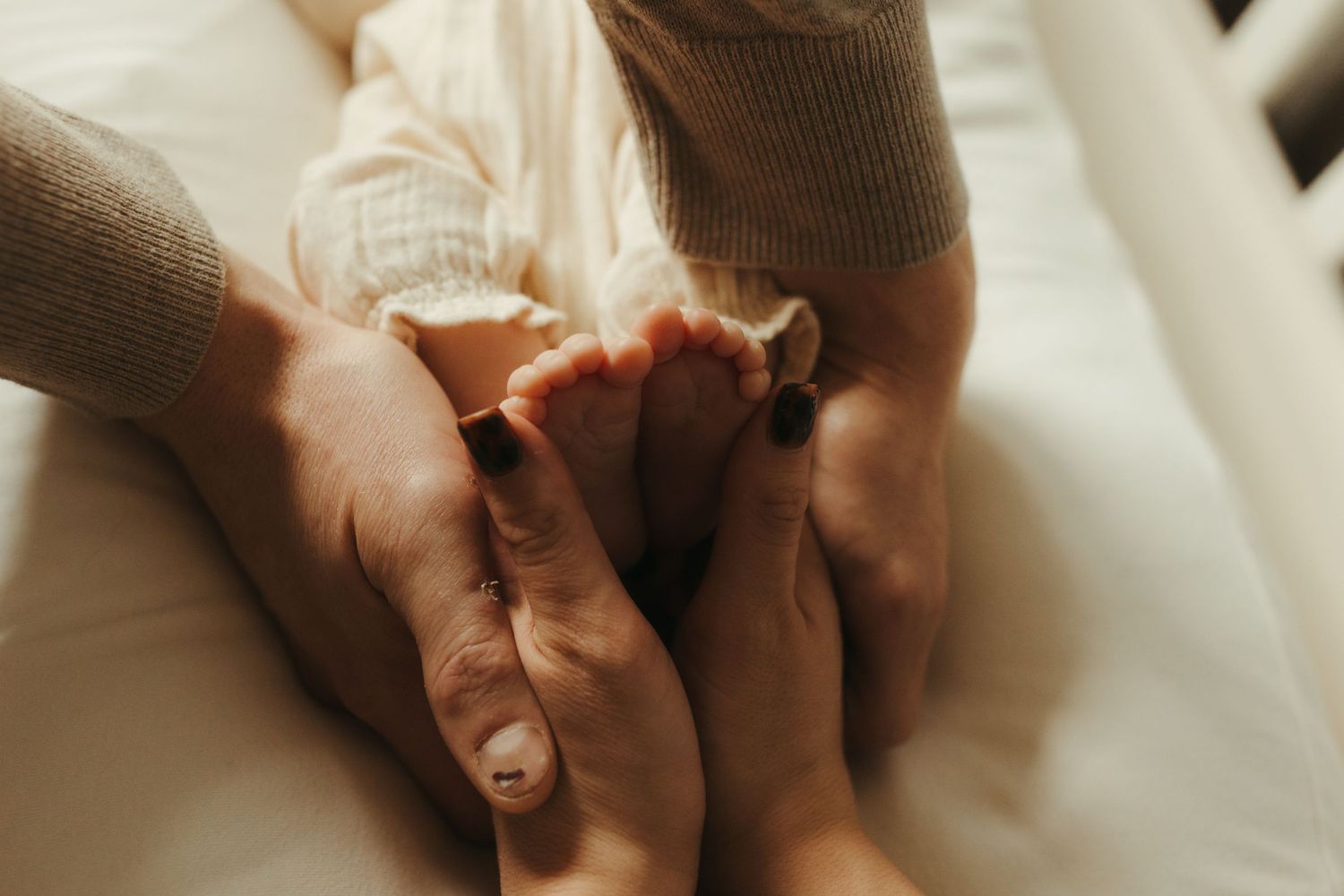 Close-up of hands tenderly touching on white bedding in warm lighting.