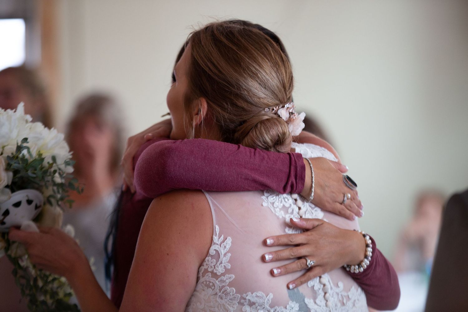 People sharing emotional embraces at a wedding reception.