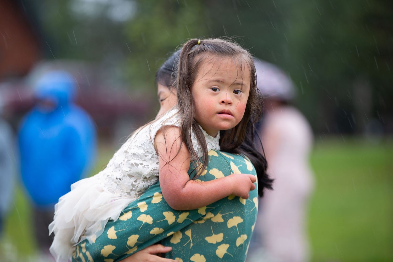 Young attendant in green patterned dress at outdoor wedding celebration.